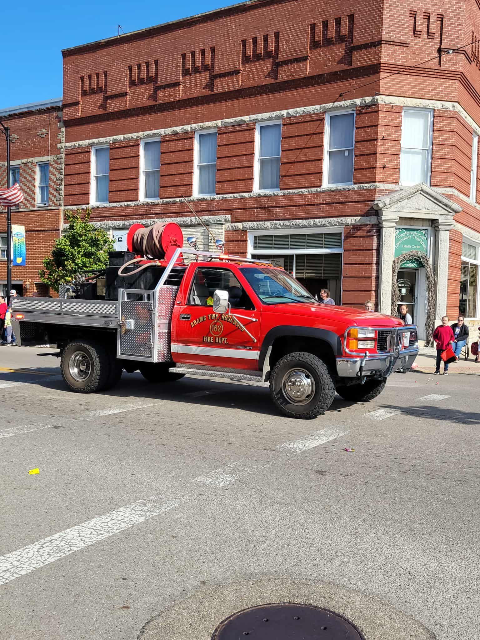 Red fire truck on a street with a brick building in the background.