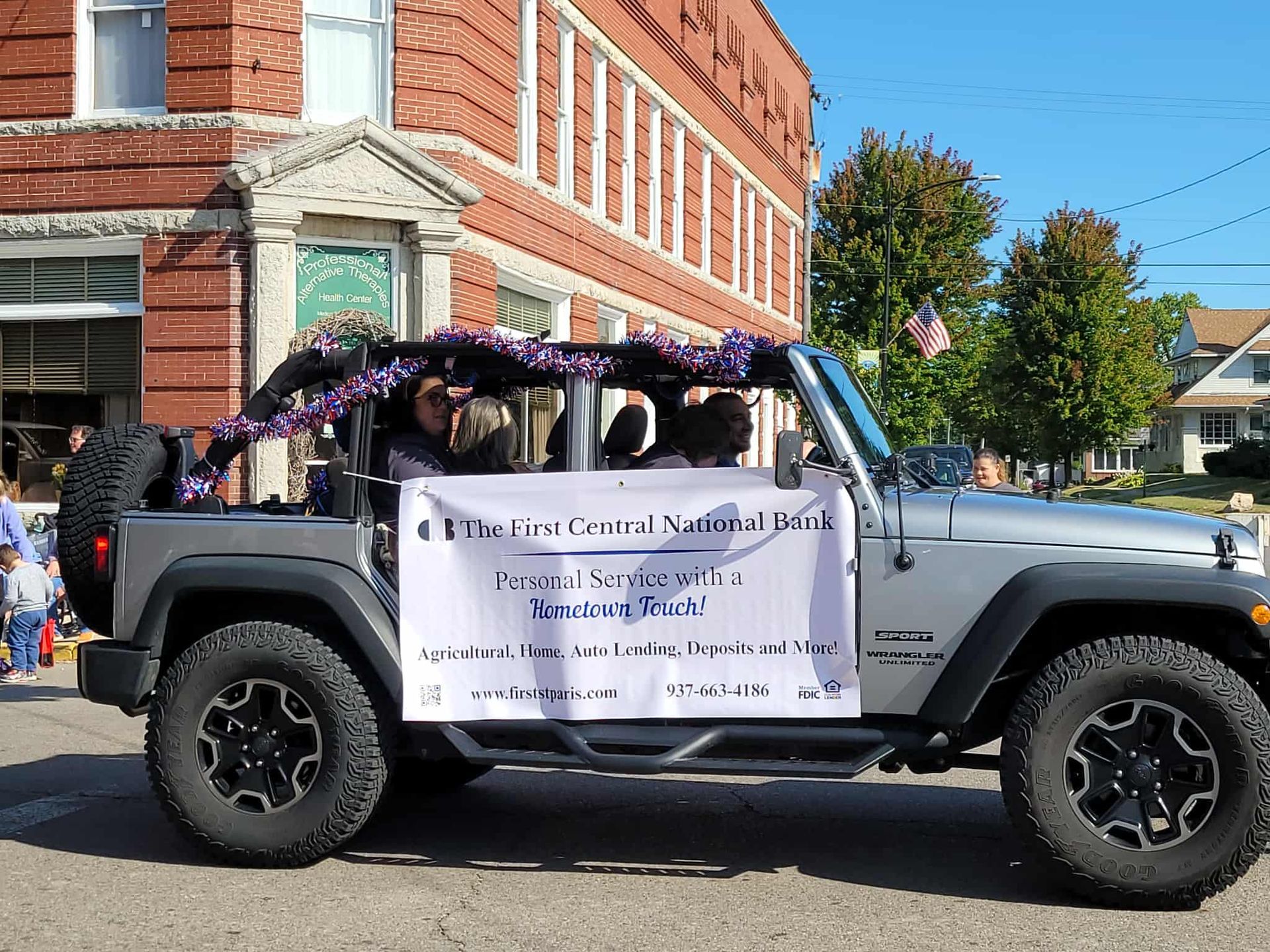 Grey Jeep in parade, banner reads: