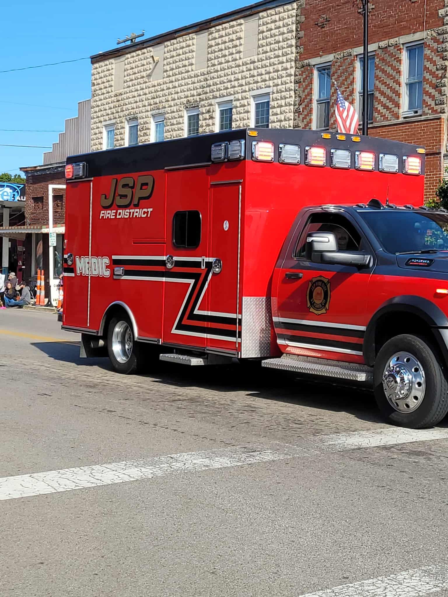 Red and black JSP EMS ambulance in a parade.