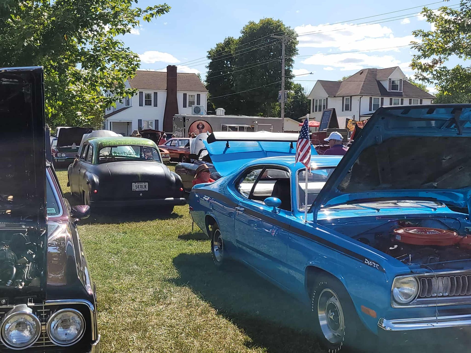 Classic cars on display at an outdoor car show on a sunny day.