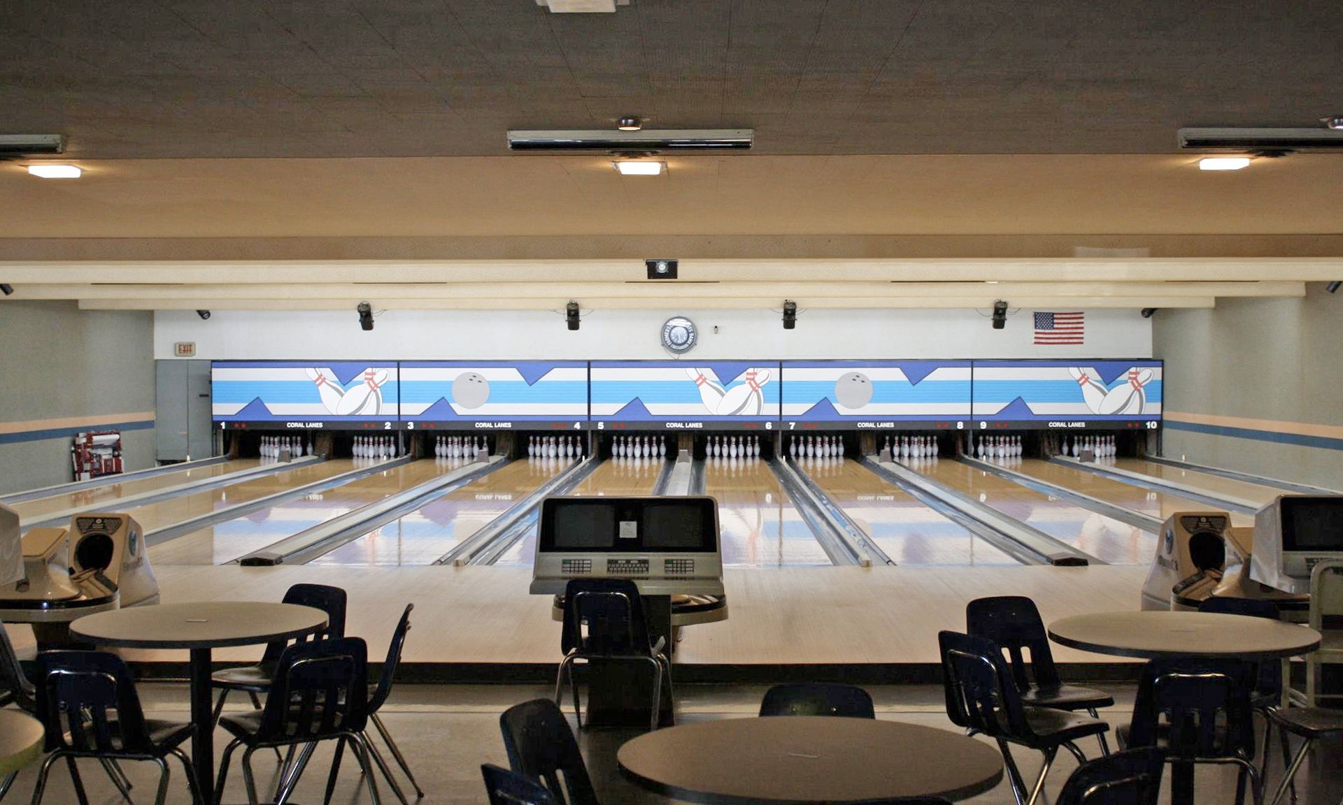 Bowling alley interior with multiple lanes, tables, and chairs.