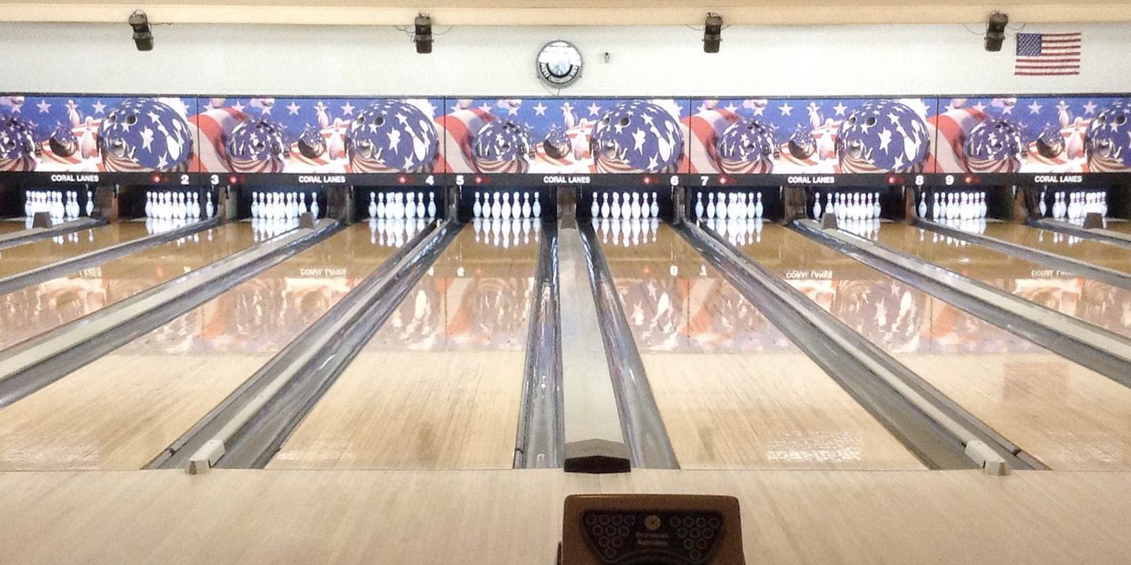 Bowling alley with multiple lanes and pins set up, patriotic decor in the background.