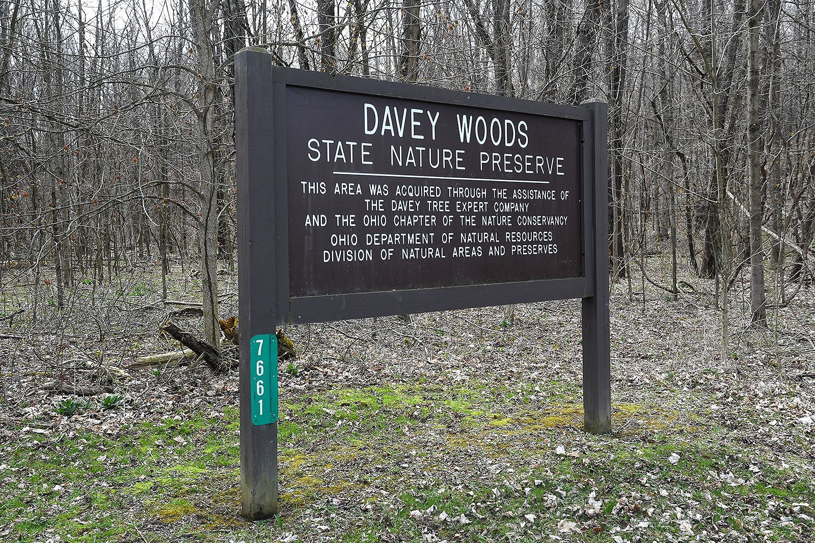 Sign for Davey Woods State Nature Preserve with text on brown background.