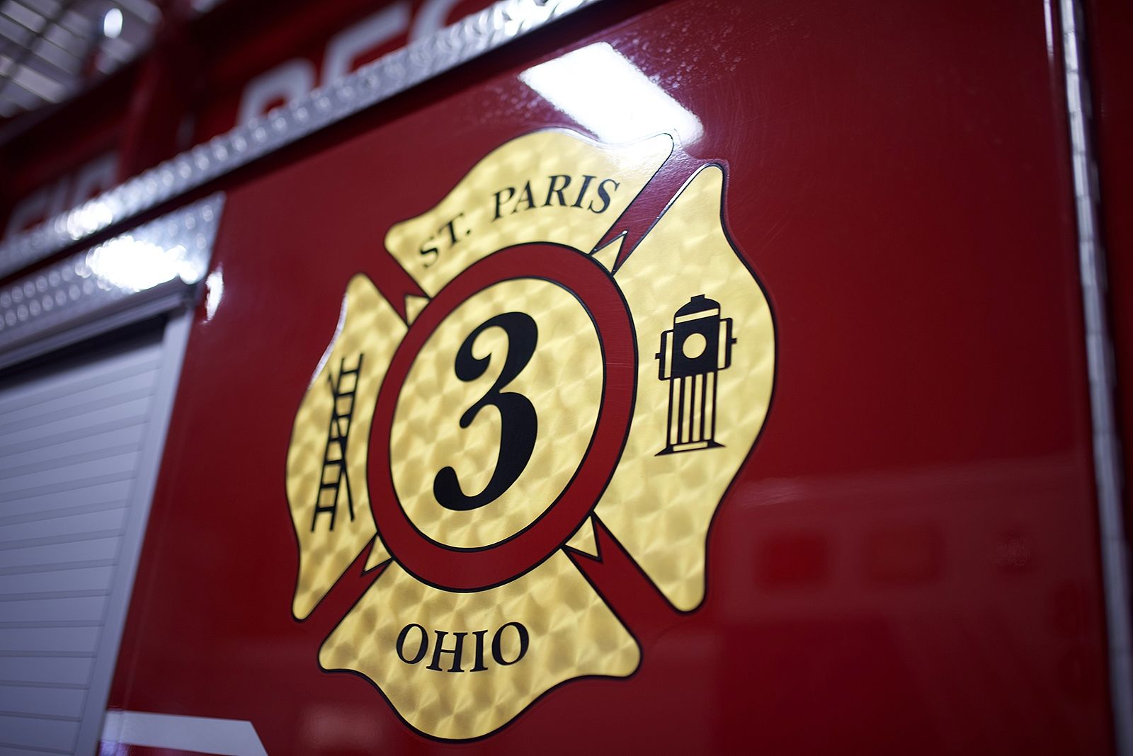 St. Paris, Ohio fire department emblem on red vehicle. Gold Maltese cross with number