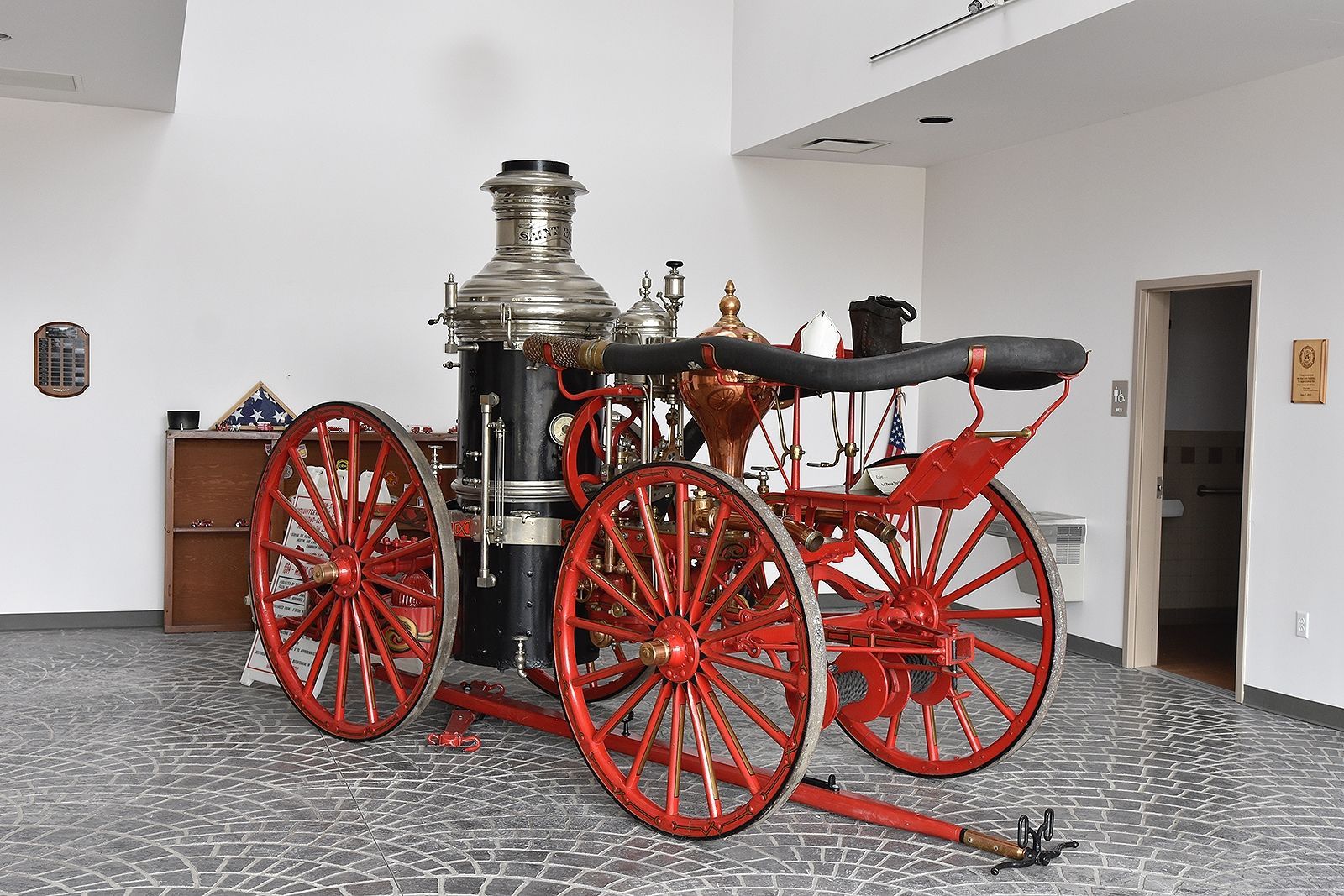 Antique red and black fire engine on display in a museum.
