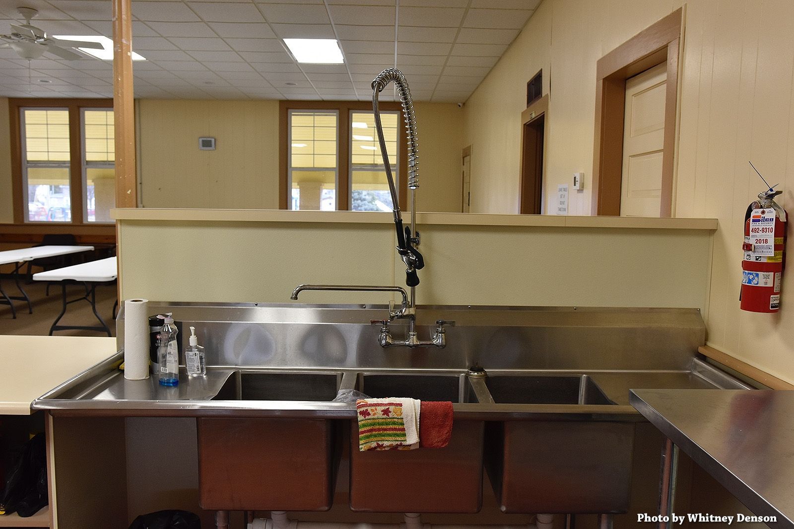 Kitchen with stainless steel sinks, a tall faucet, and a fire extinguisher on the wall.