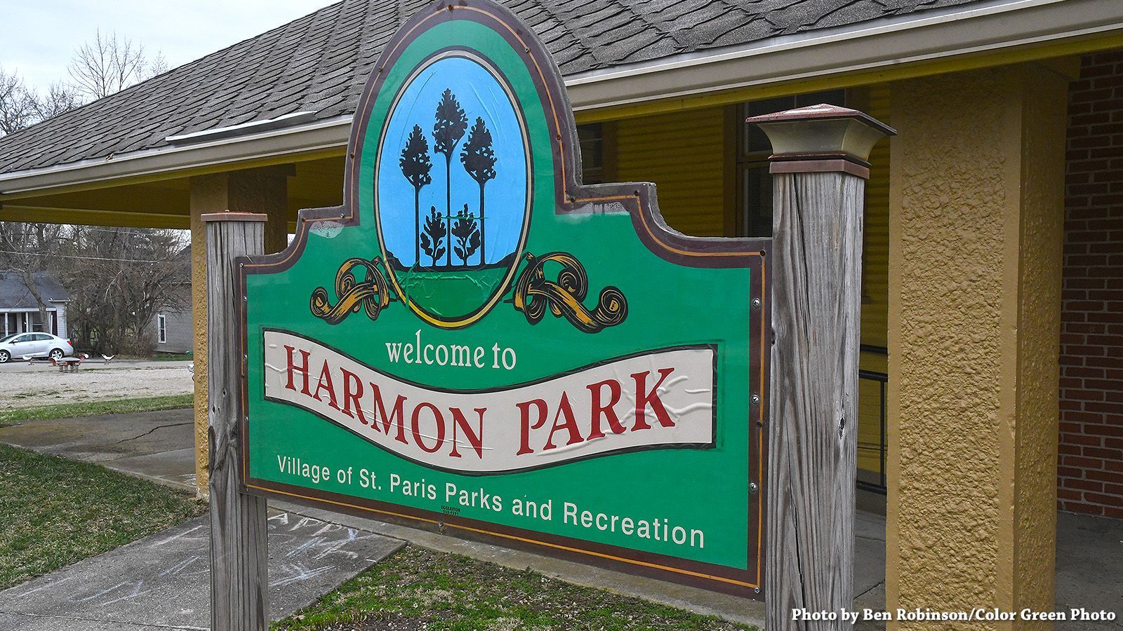 Sign for Harmon Park, green with white text, blue trees graphic.