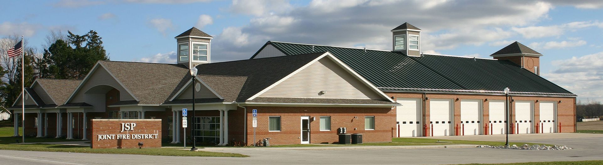Fire station with brick facade and multiple garage doors under cloudy sky.