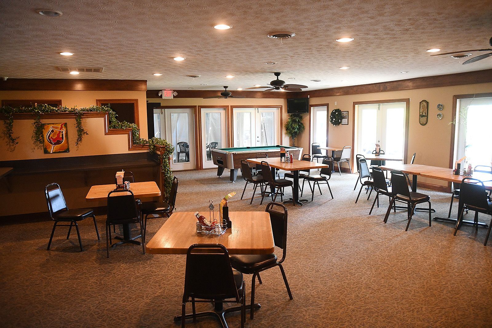 Restaurant dining area with tables, chairs, pool table, and windows.