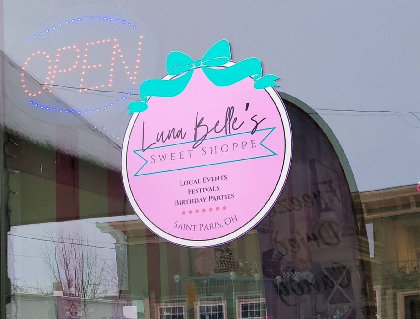 Window of Luna Belle's Sweet Shoppe, displaying signage for candy, ice cream, and gifts, with an 