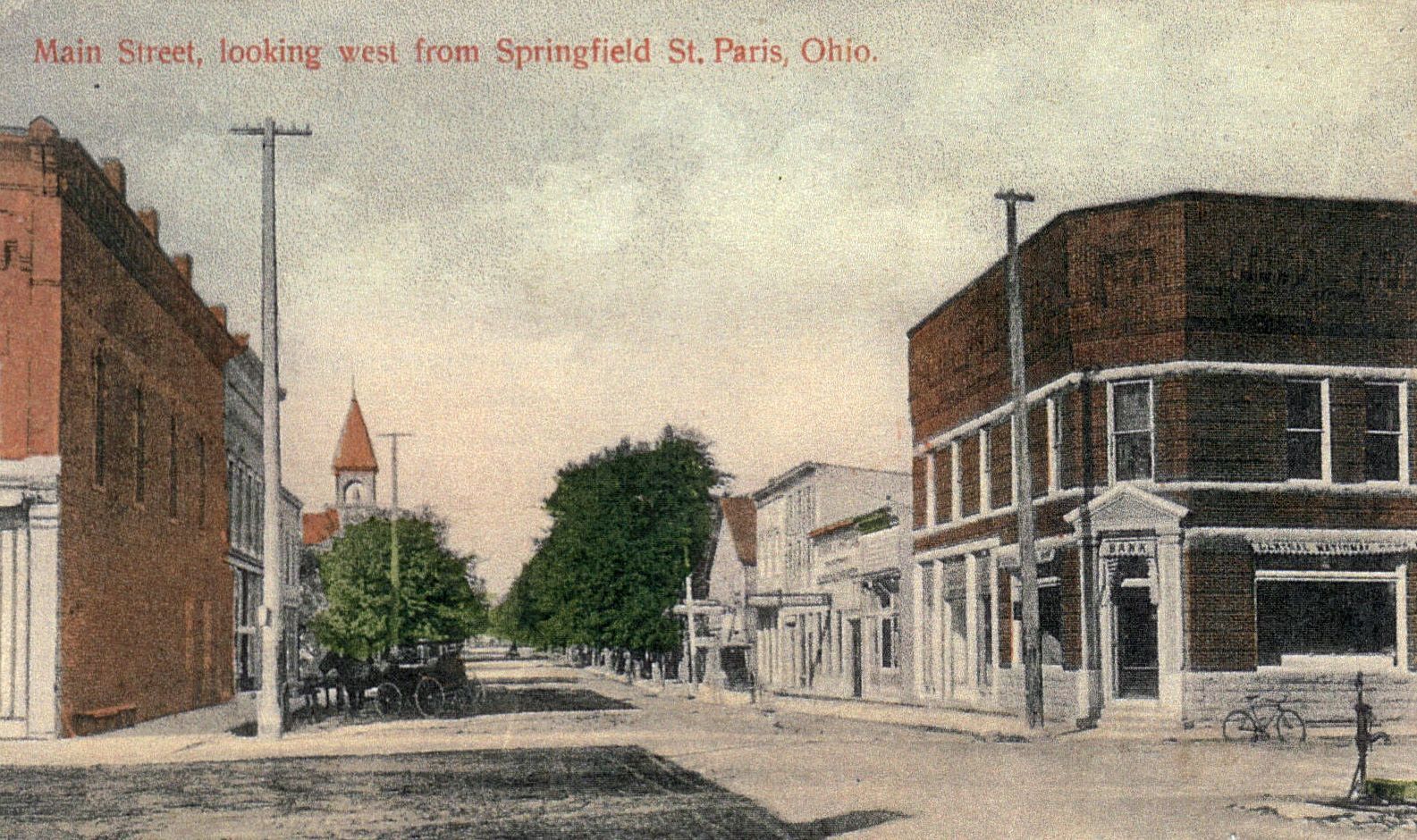 Street view in St. Paris, Ohio, showing Main Street. Brick buildings with a church steeple is visible in the distance.