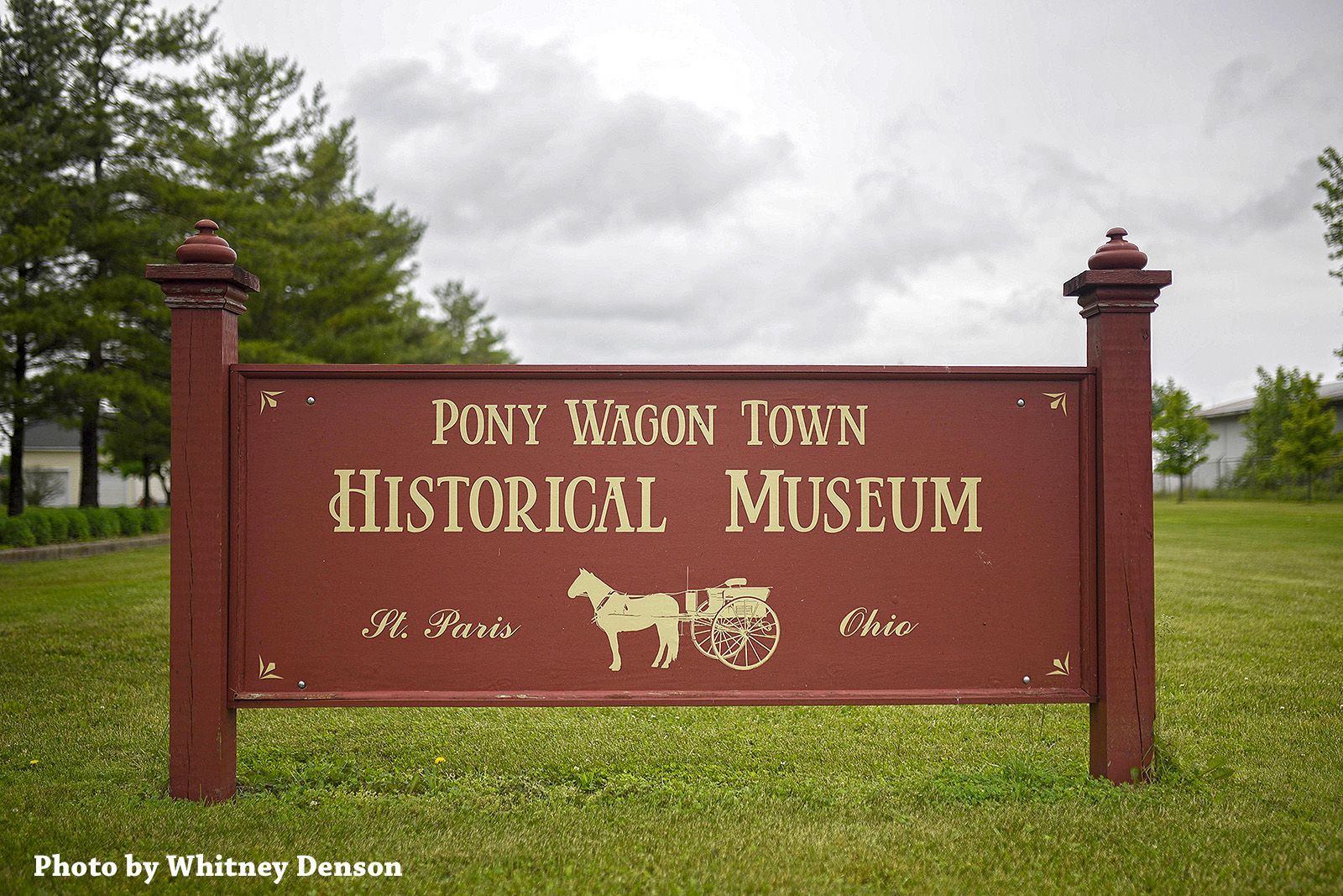 Sign for Pony Wagon Town Historical Museum, brown with gold lettering, logo of horse and carriage.