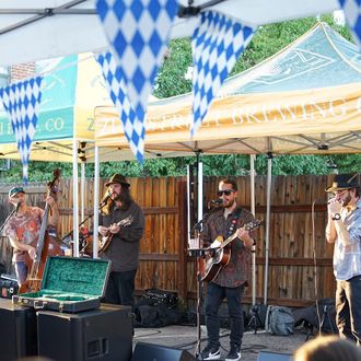 a man playing a guitar in front of a tent that says brewing