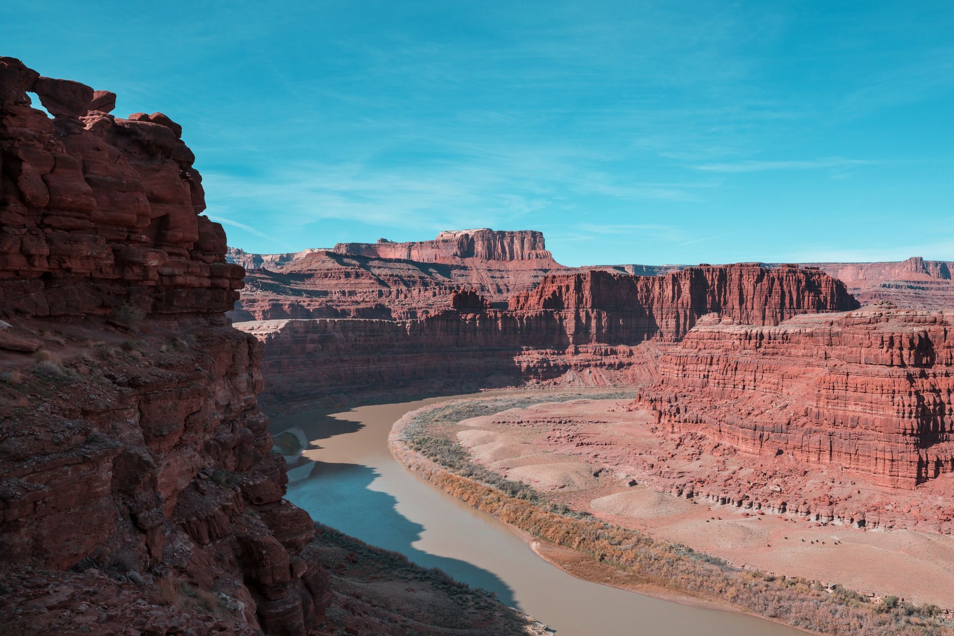 Red canyon overlook above a winding river under a clear blue sky