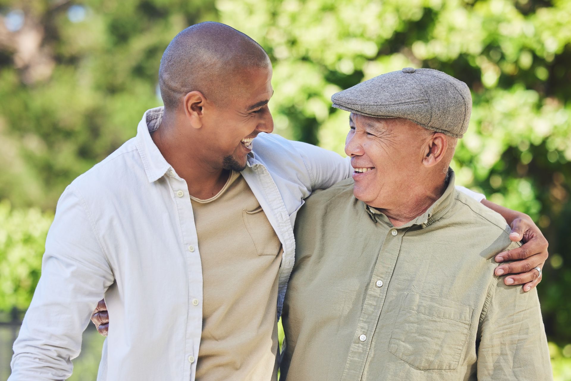Two people smiling and embracing outdoors in a sunny green park