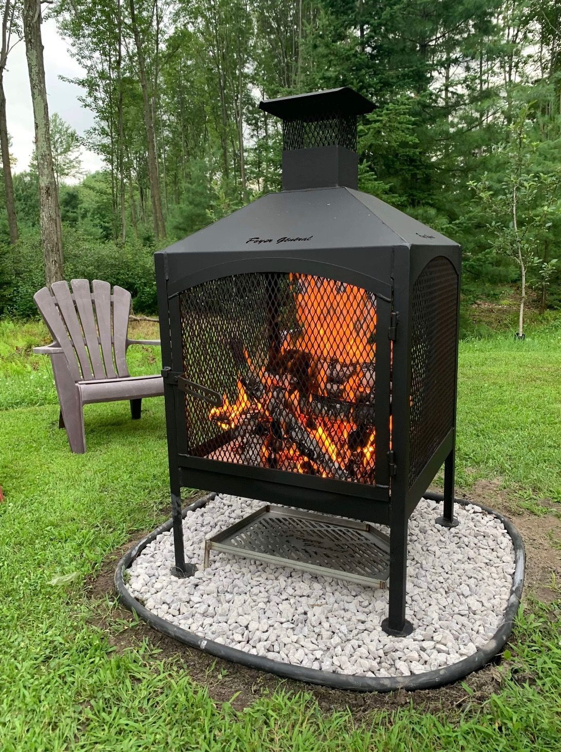 Foyer avec des flammes brûlantes dans une cour arrière, à côté d'une chaise Adirondack.
