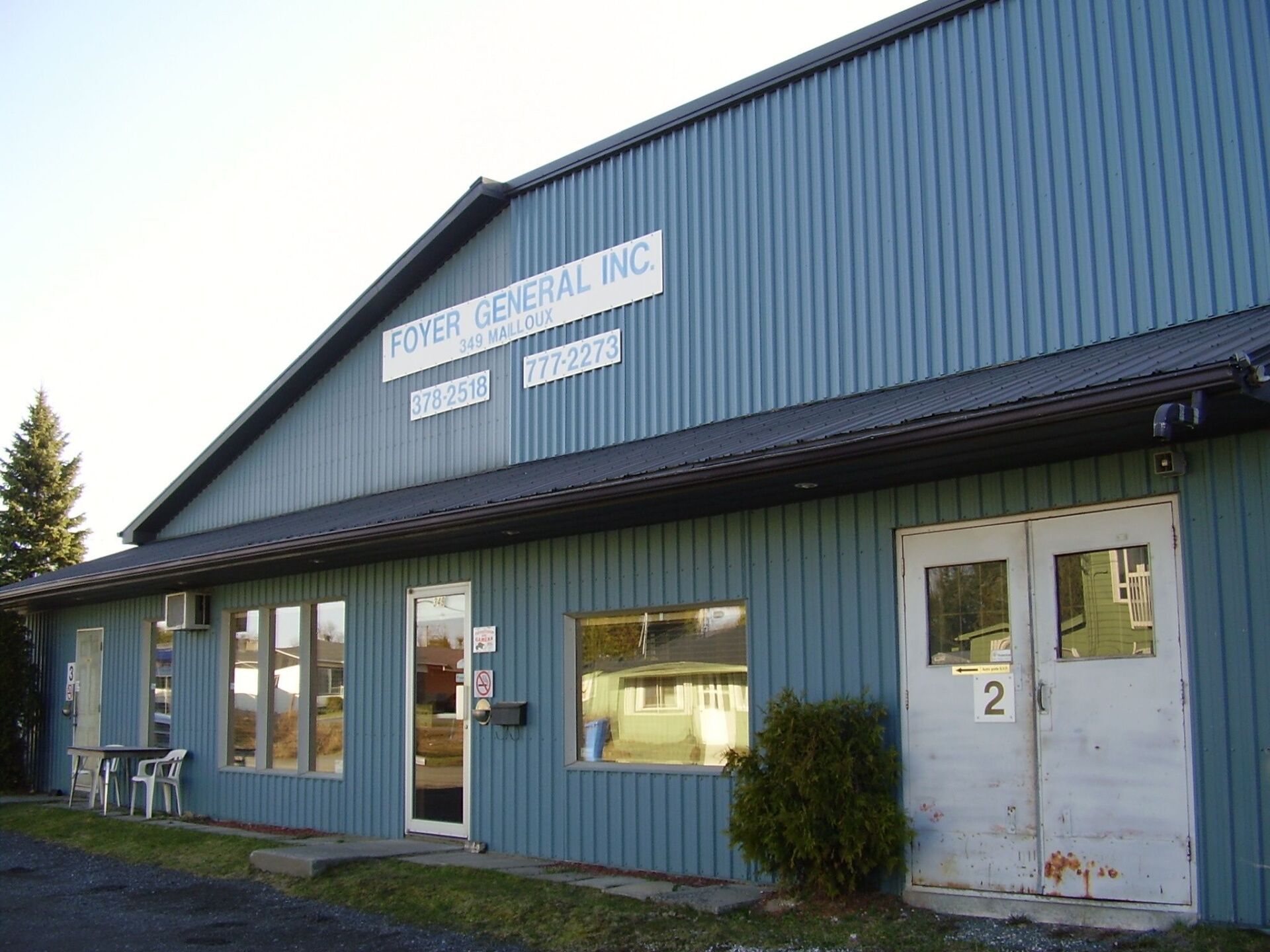 Bâtiment commercial bleu avec enseigne : « ROYER GENERAL INC. », fenêtres et porte double marquée « 2 ».