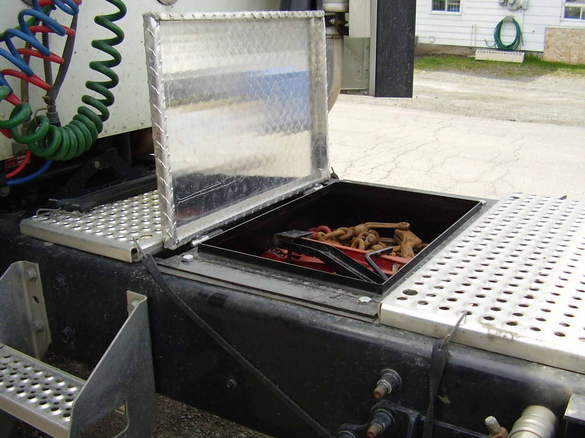 Boîte à outils de camion ouverte, montrant des chaînes et des outils, avec une surface en plaque de diamant.