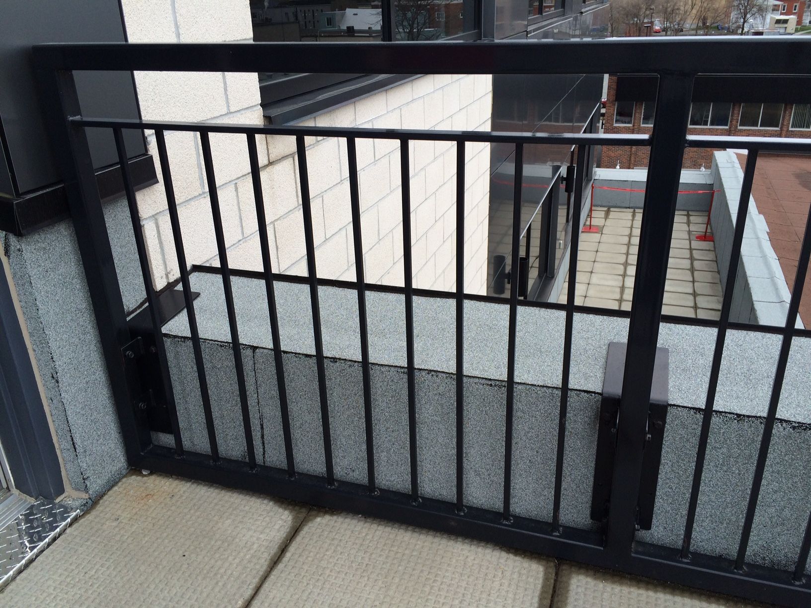 Garde-corps de balcon en métal noir avec une base en béton à l'extérieur d'un bâtiment.