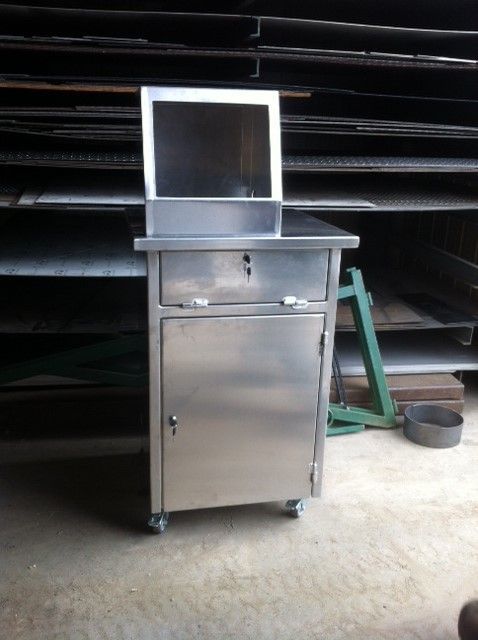 Chariot médical en acier inoxydable avec tiroir, armoire et support de moniteur sur roulettes.