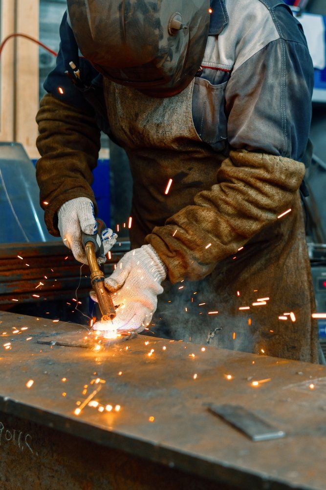 Un soudeur en tenue de protection découpe du métal, des étincelles jaillissant dans un atelier industriel