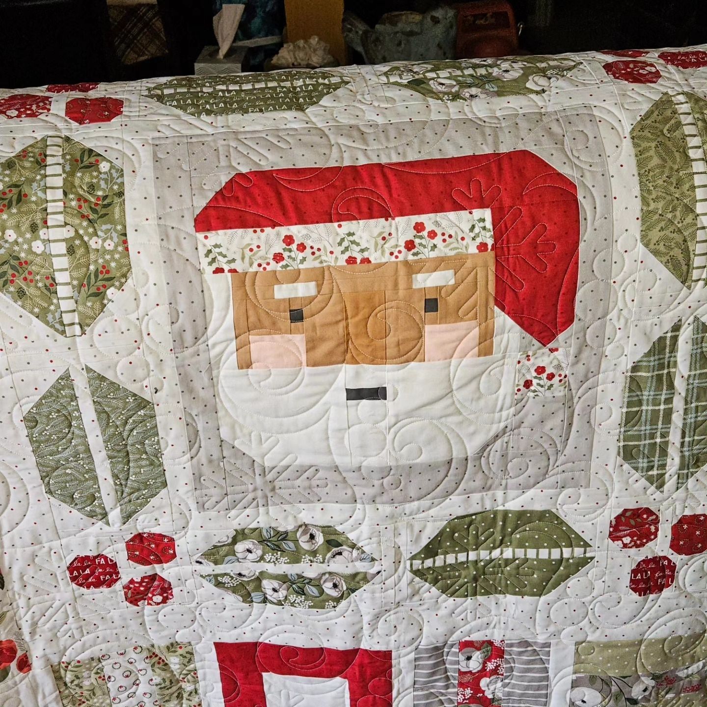 Quilted Santa face with red hat, white beard, and holly and berry patterns on a white background