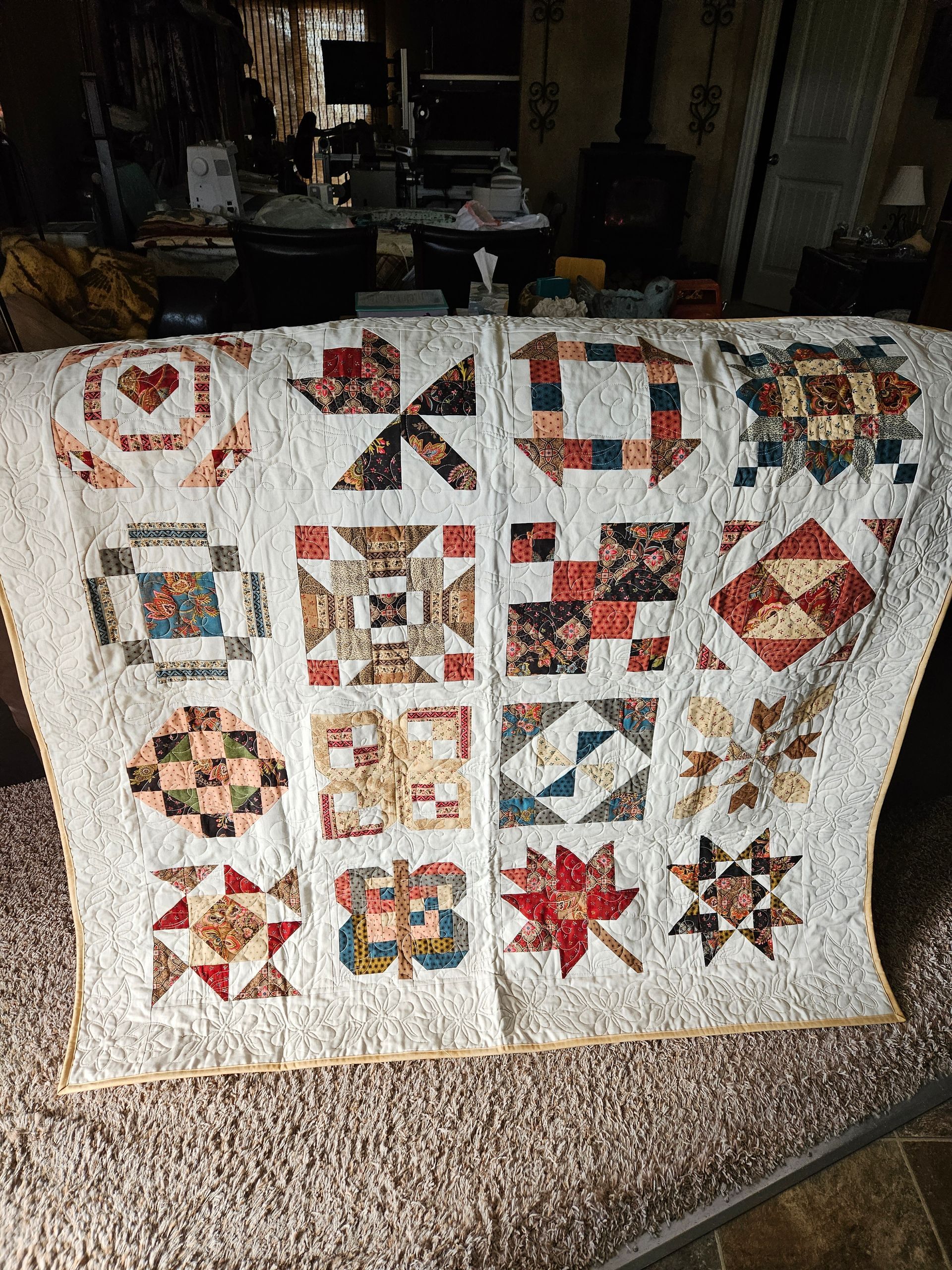 Patchwork quilt draped over a couch, with colorful square and star quilt blocks on a white background.