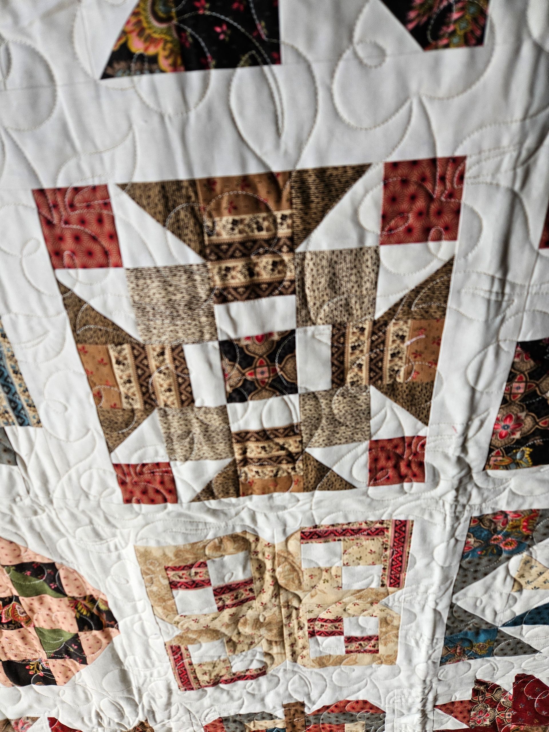 Patchwork quilt with red, brown, and cream geometric star and square blocks.