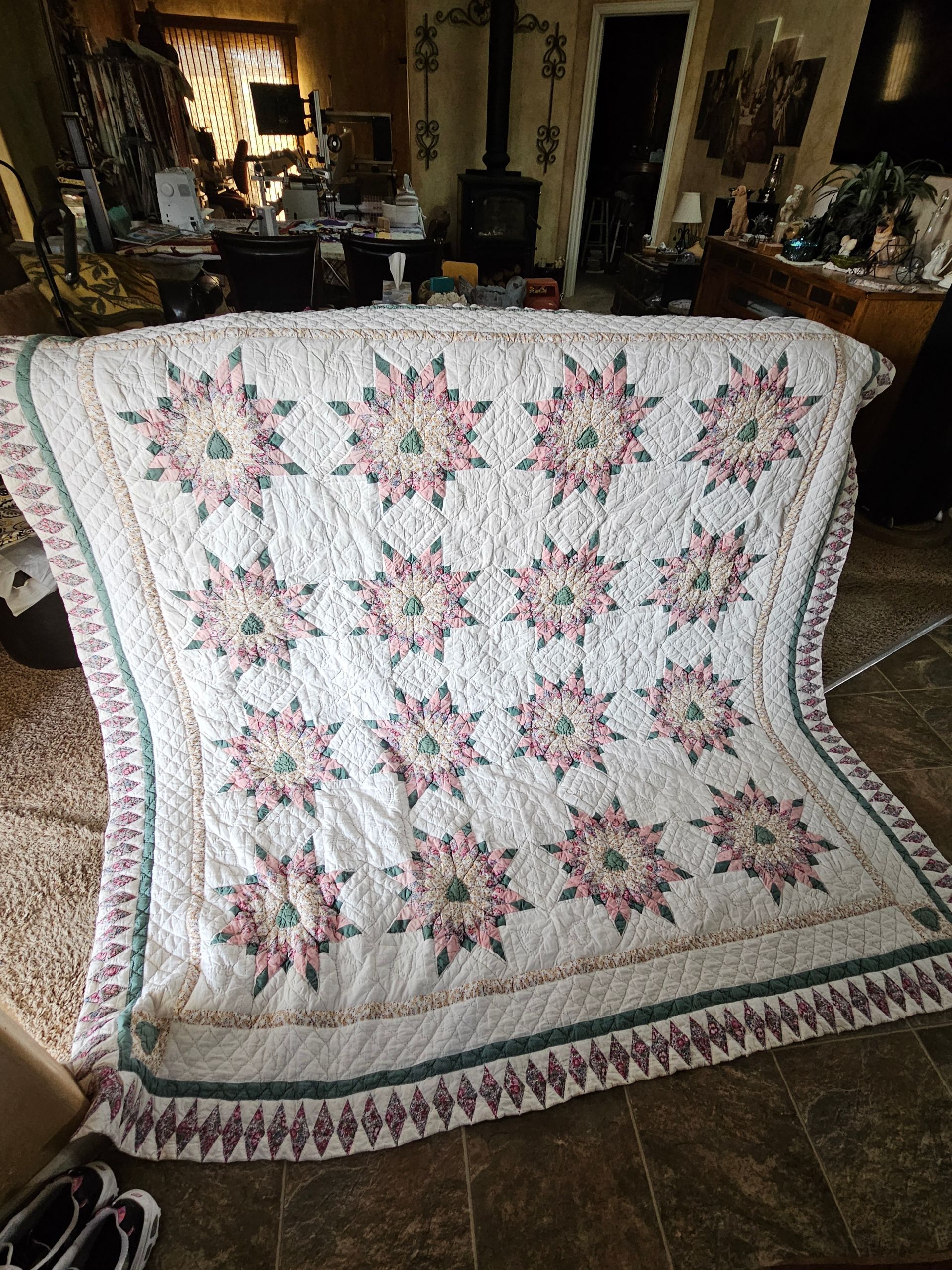 Quilt with pink floral star pattern draped over a couch in a living room