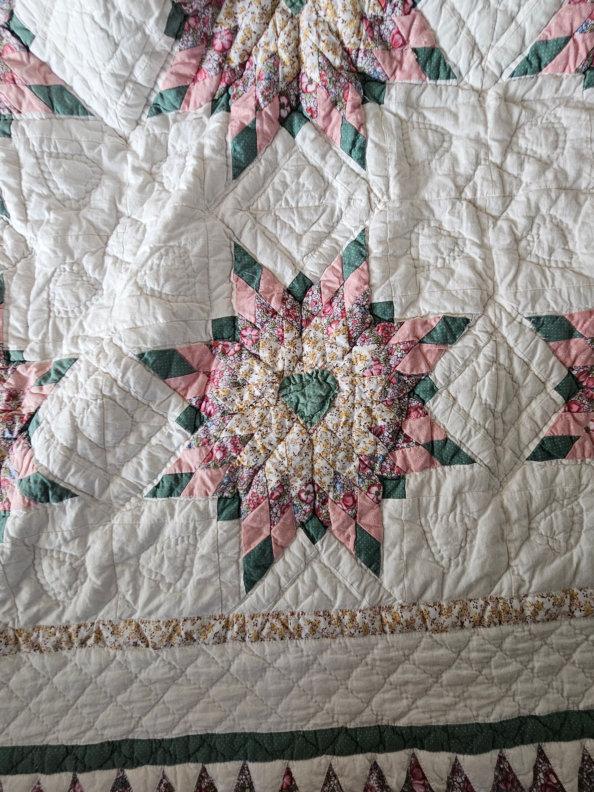 Quilted textile with white, pink, and green starburst patches and a decorative border