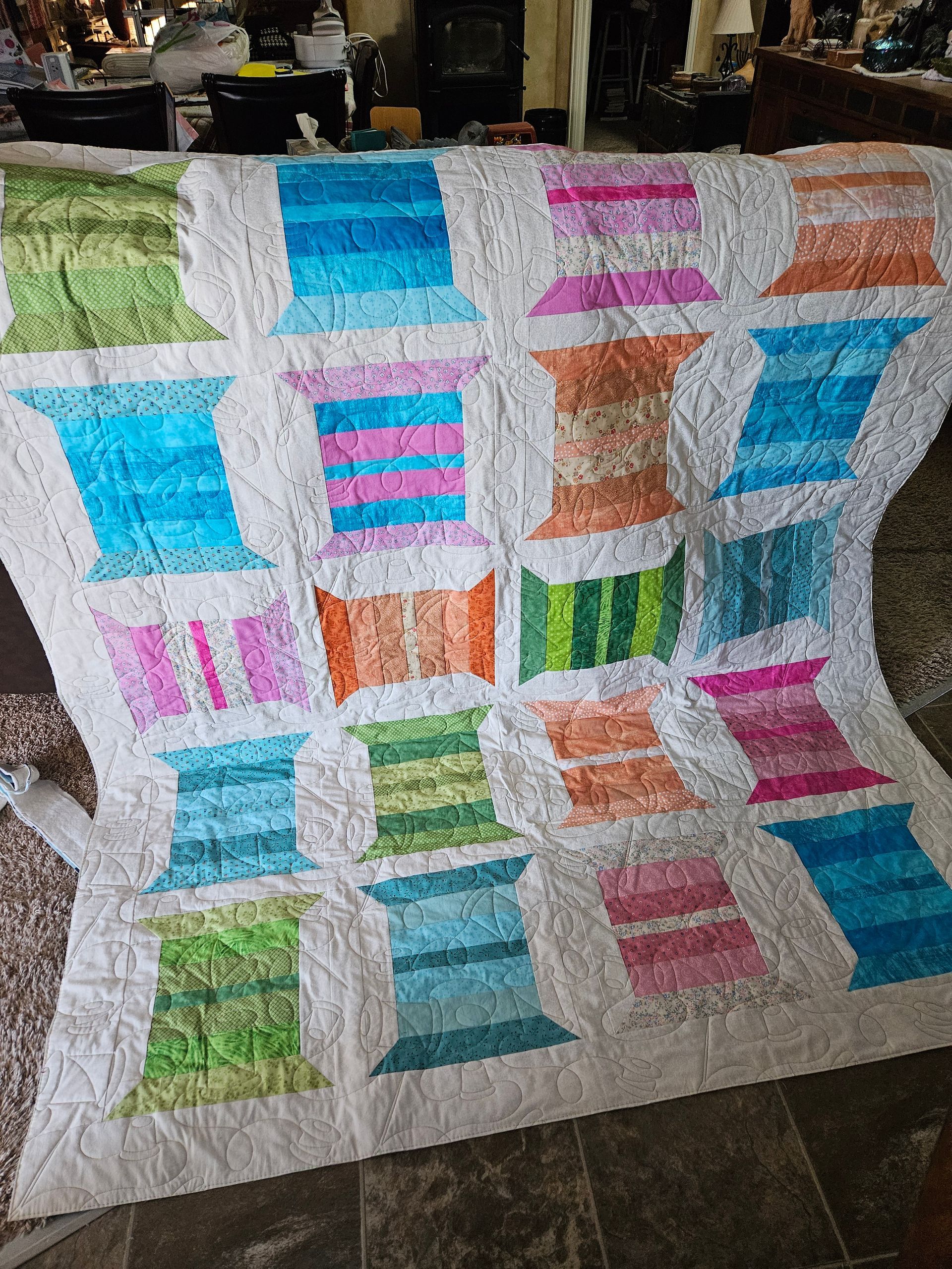Patchwork quilt with colorful striped and solid blocks in blue, pink, orange, and green on a white background