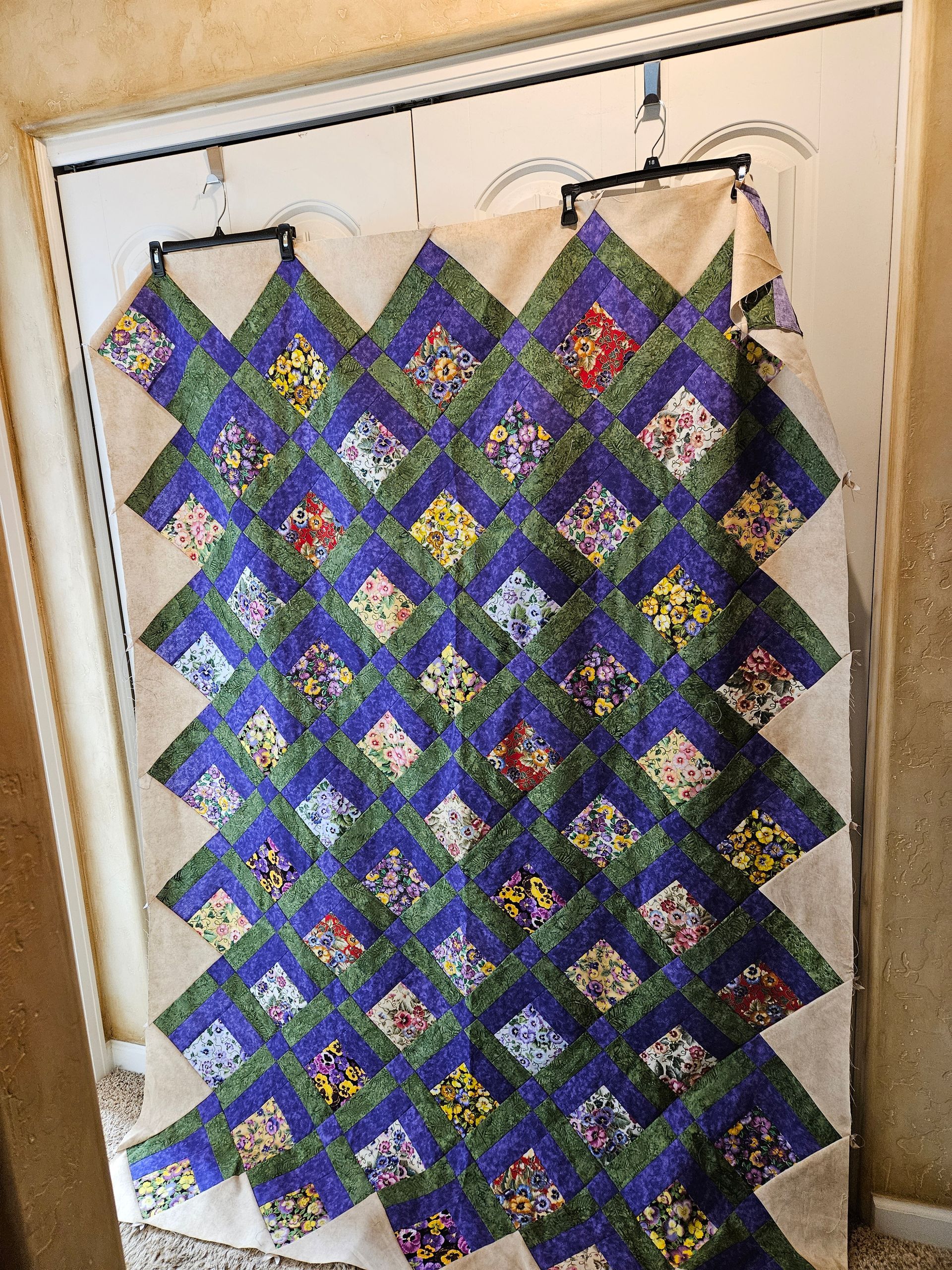 Colorful blue, green, and purple patchwork quilt hanging on a closet door.