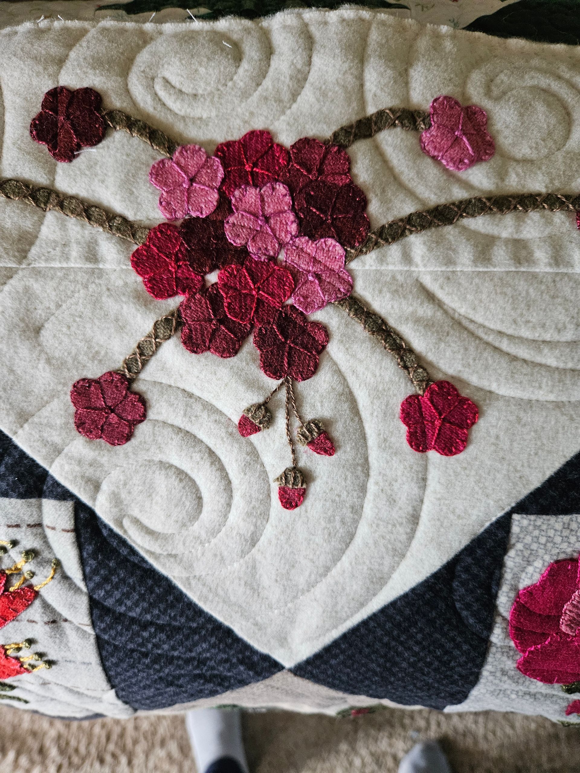 Close-up of a quilt with pink floral embroidery on a cream quilted background