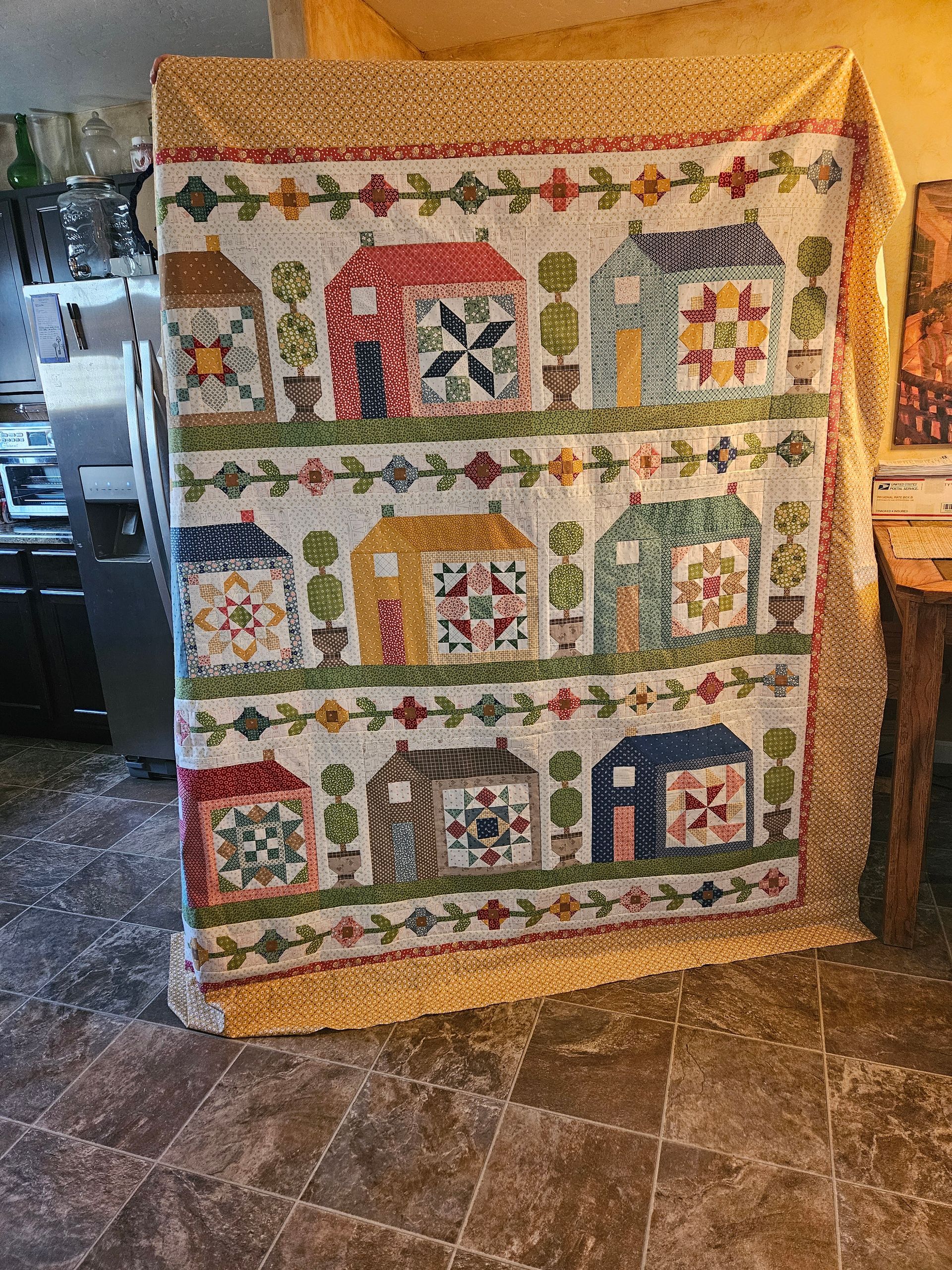 Colorful quilt with house patterns draped over a chair in a home interior