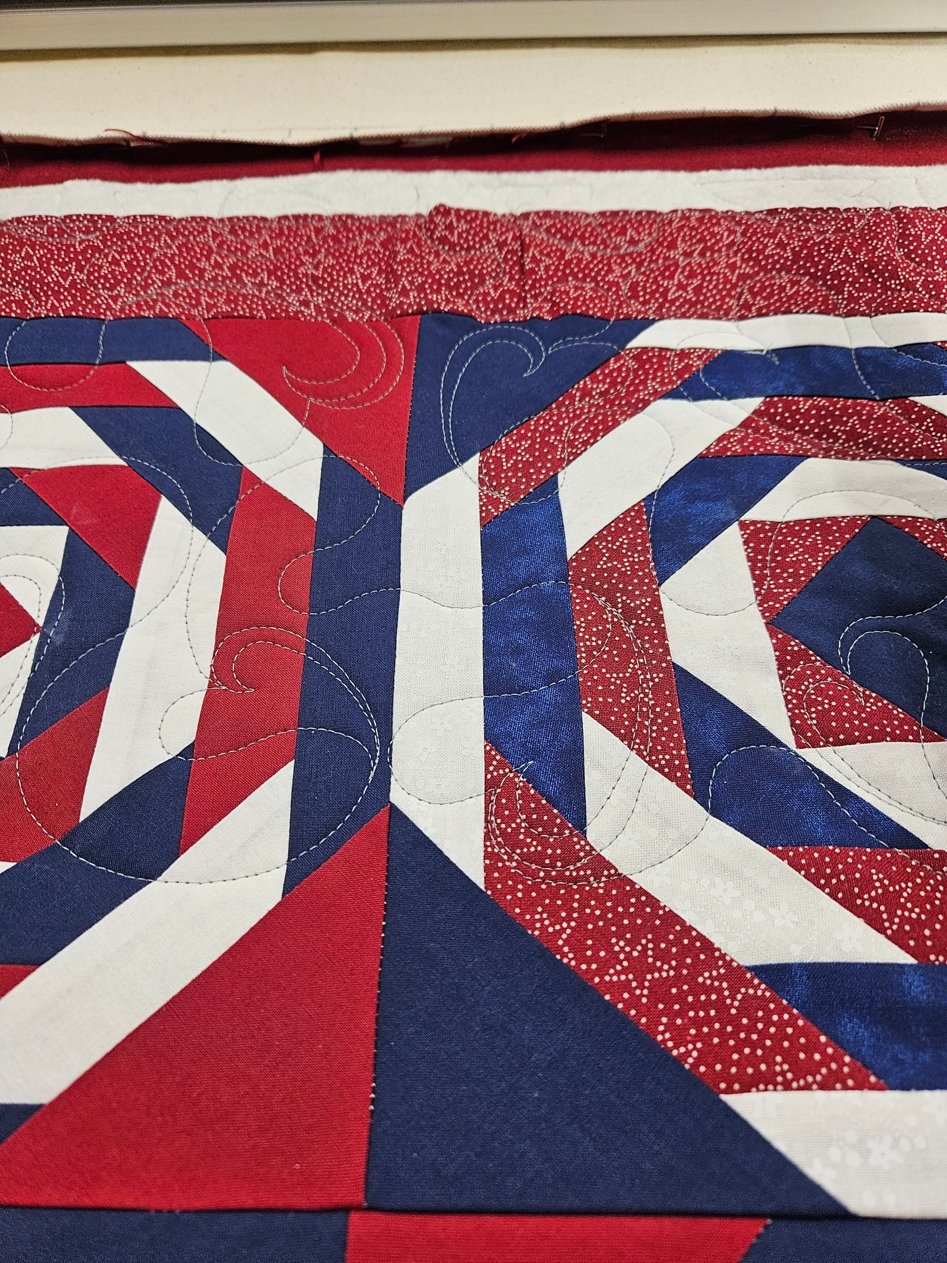 Red, white, and blue geometric quilt pattern with concentric diamond and hexagon shapes