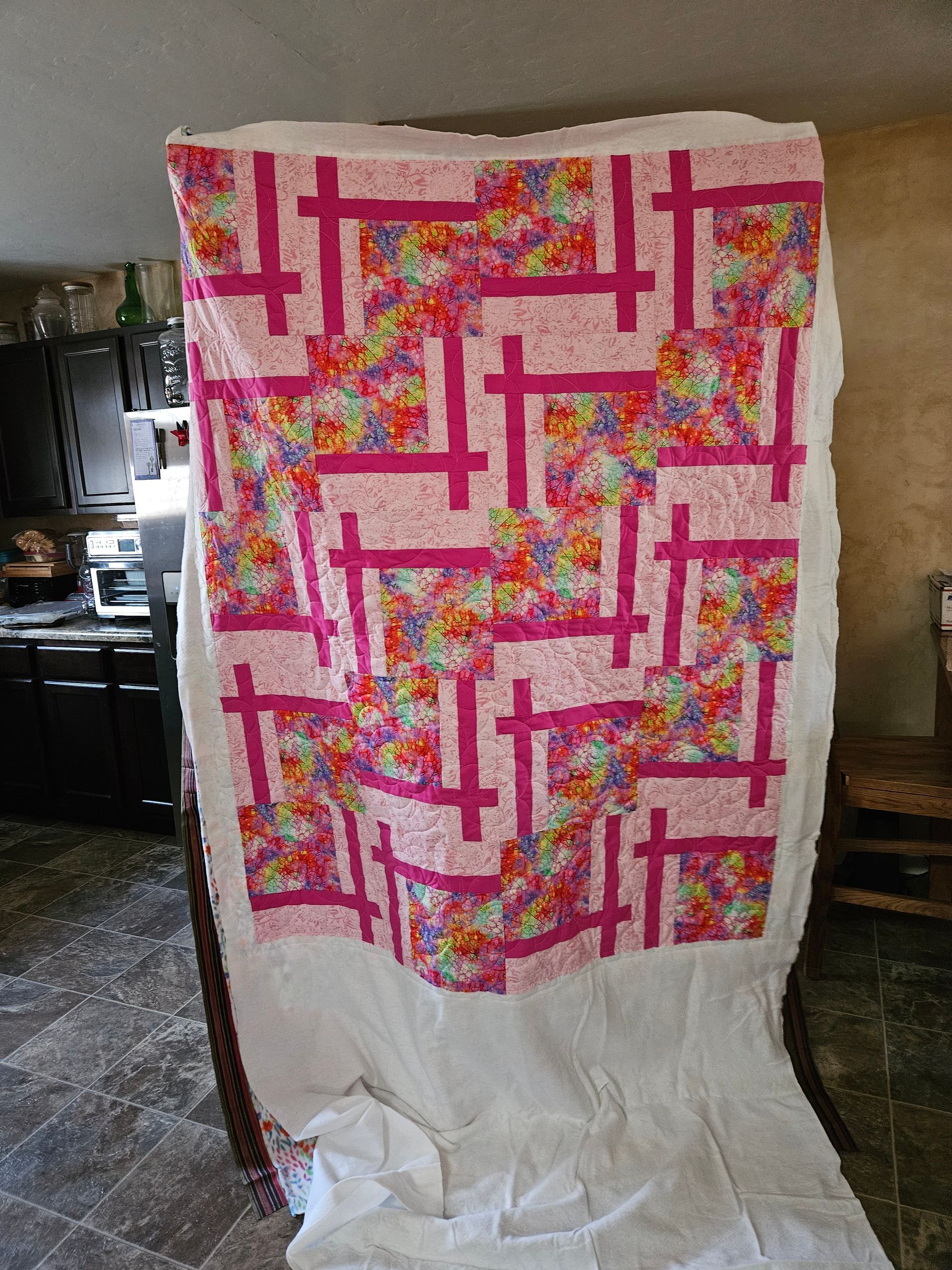 Large white sheet with a pink and multicolored geometric pattern hanging indoors