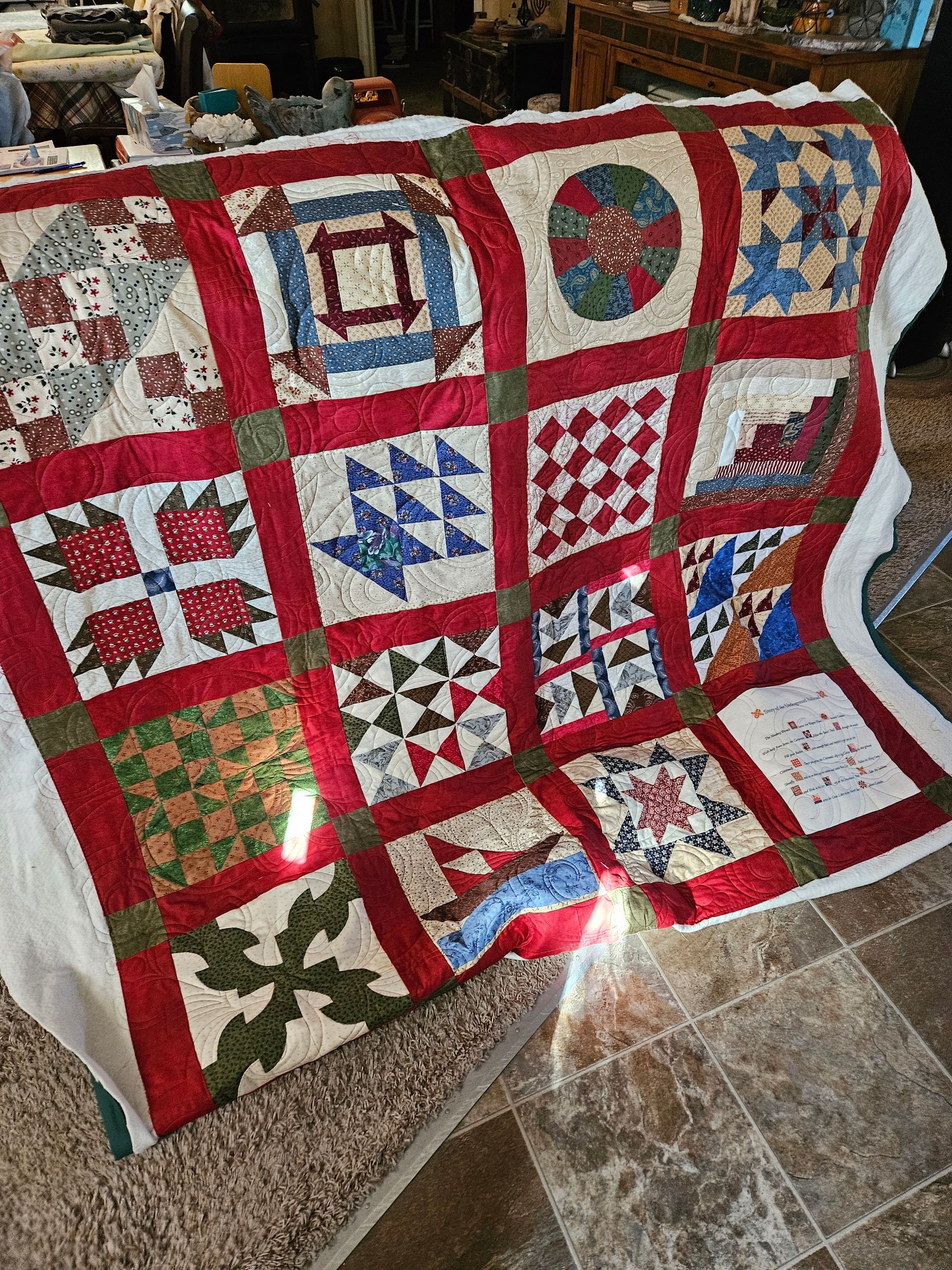 Patchwork quilt with red, green, blue, and white square patterns draped over a chair indoors