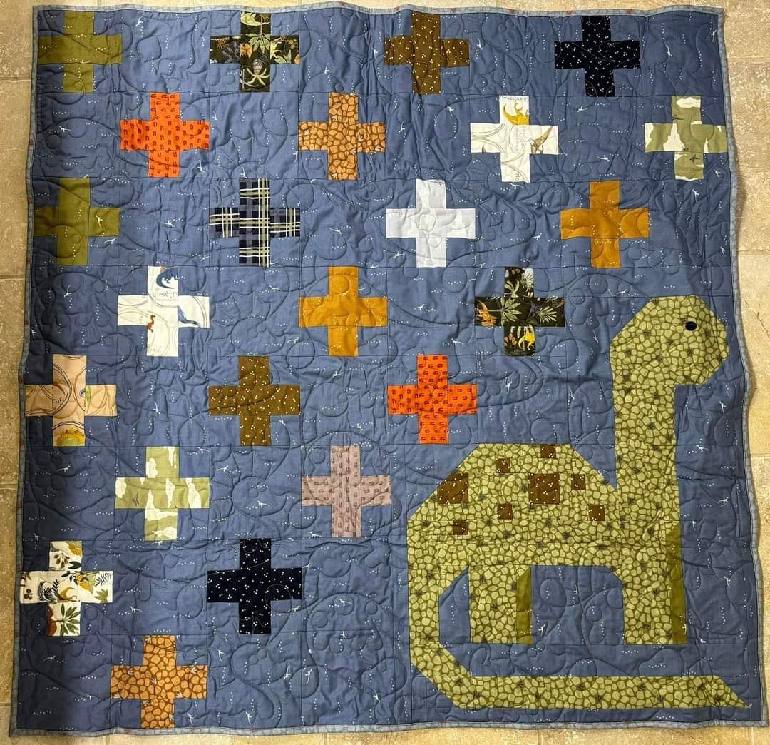 Blue quilt with colorful cross patches and a yellow giraffe appliqué on the right