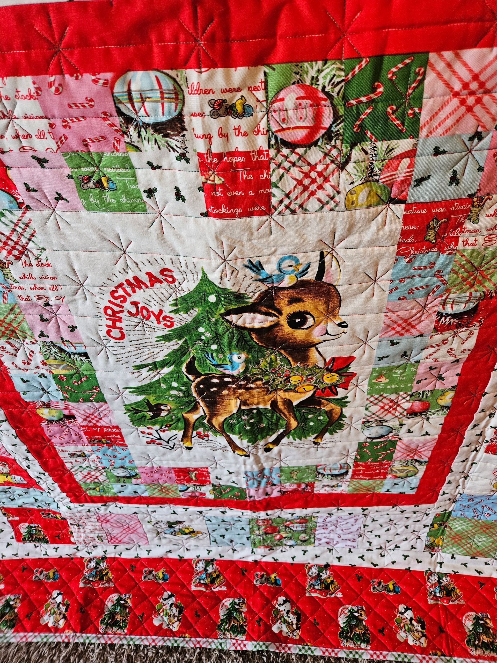 Christmas quilt with a reindeer, tree, and festive red-and-white patchwork borders