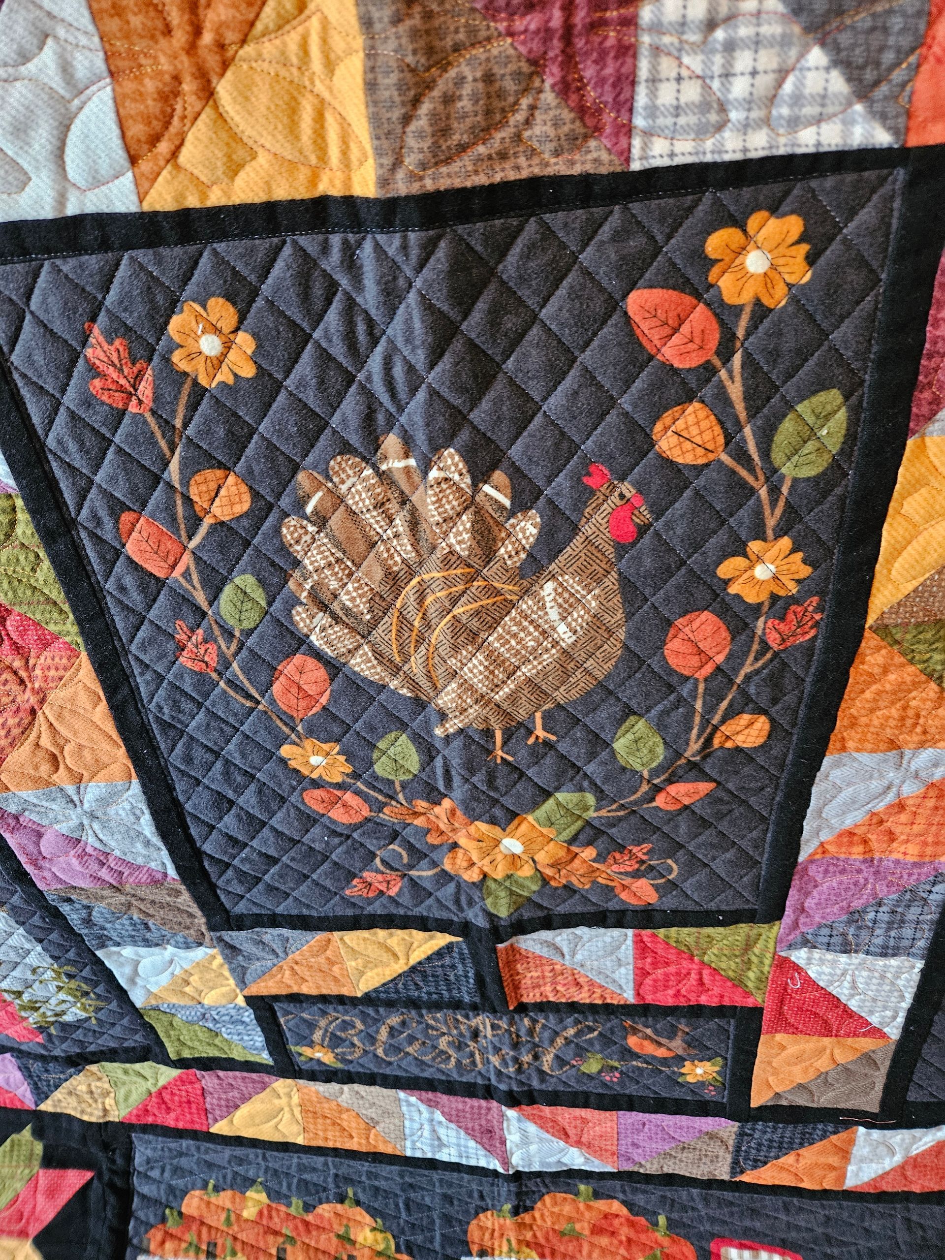 Quilted fabric wall hanging with a black floral basket and colorful patchwork border