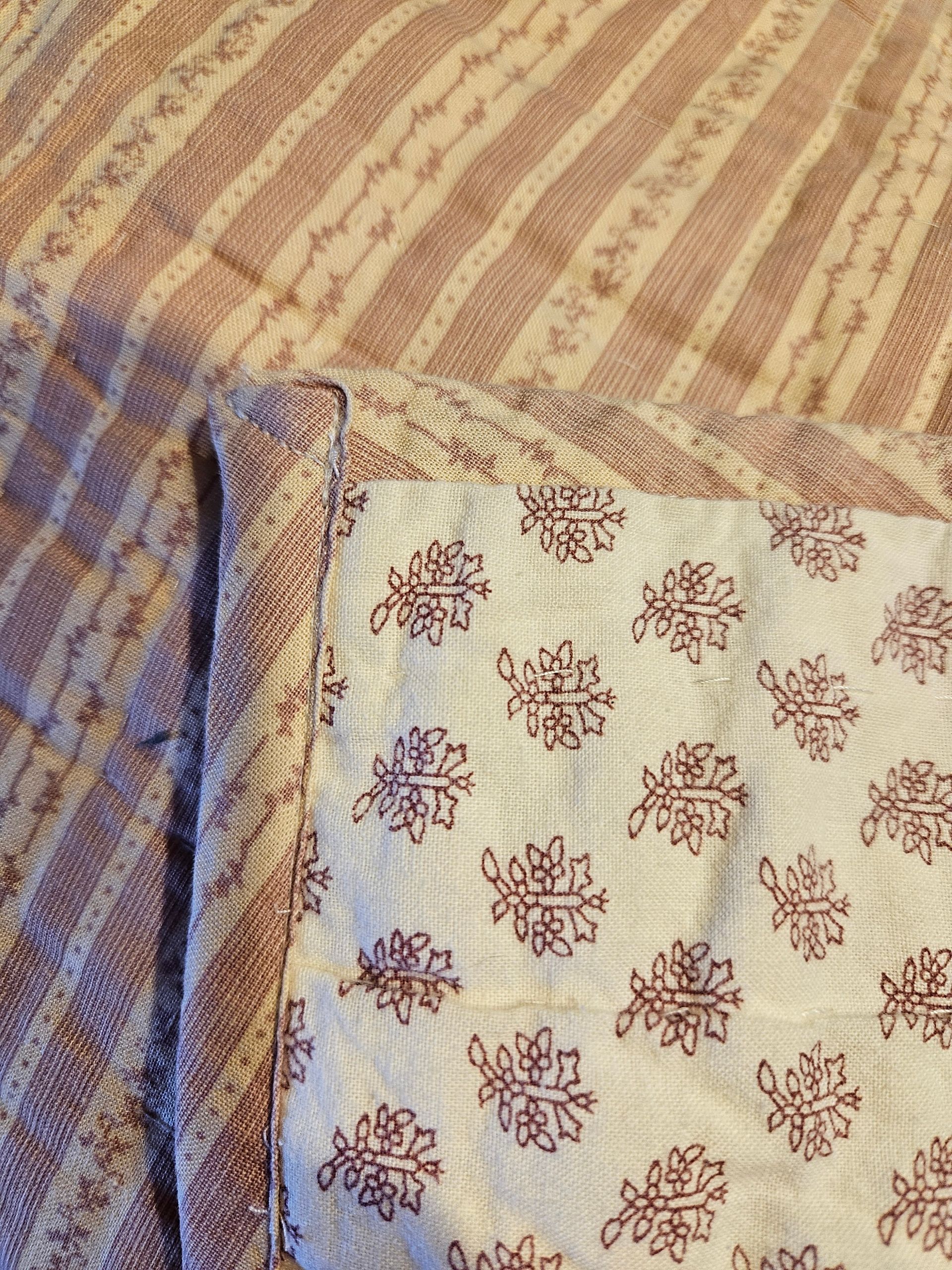 Close-up of patterned beige and maroon fabric with a folded blue border
