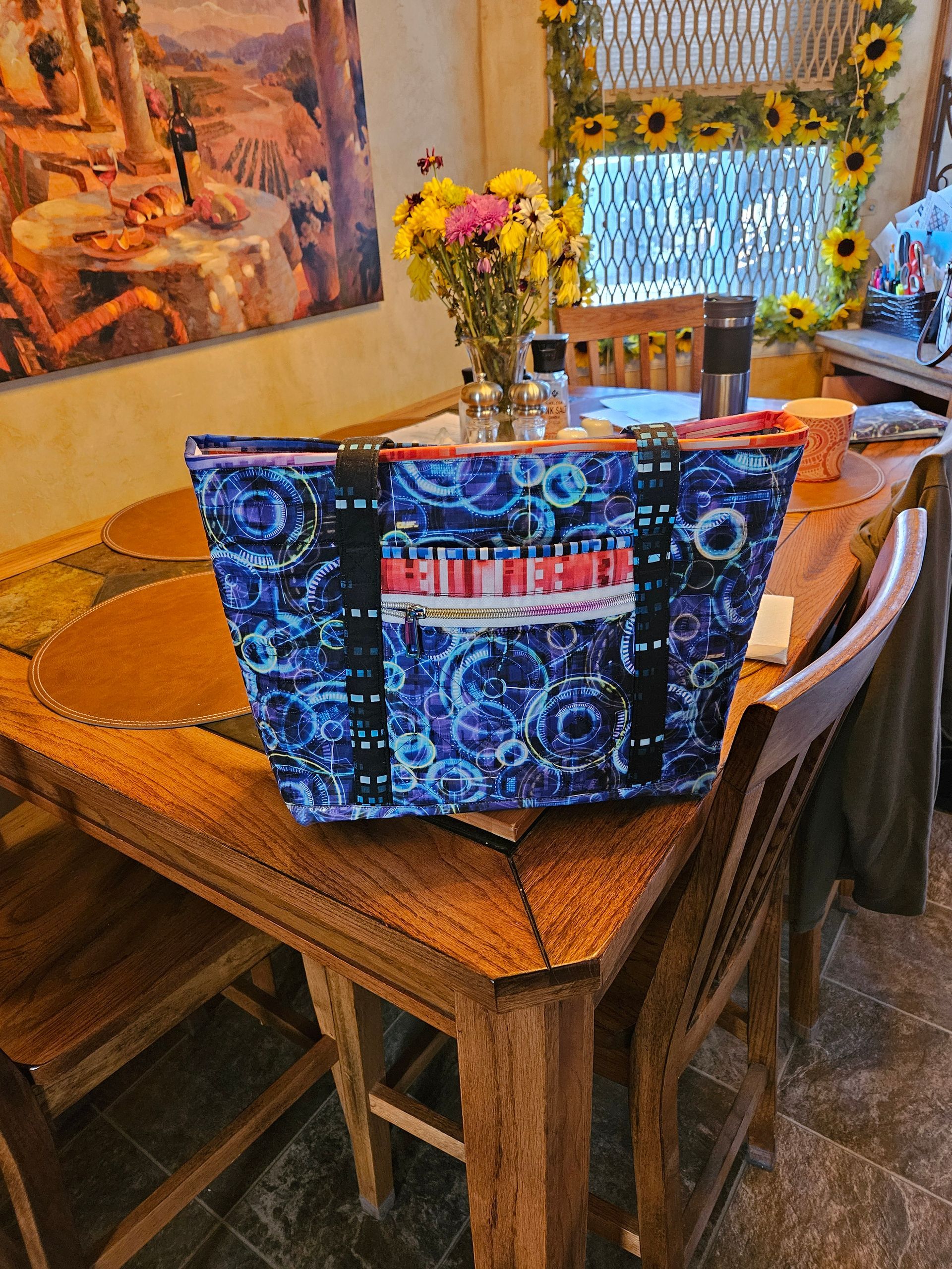 Dining table with a colorful blue tote bag and flowers in a warm, decorated room