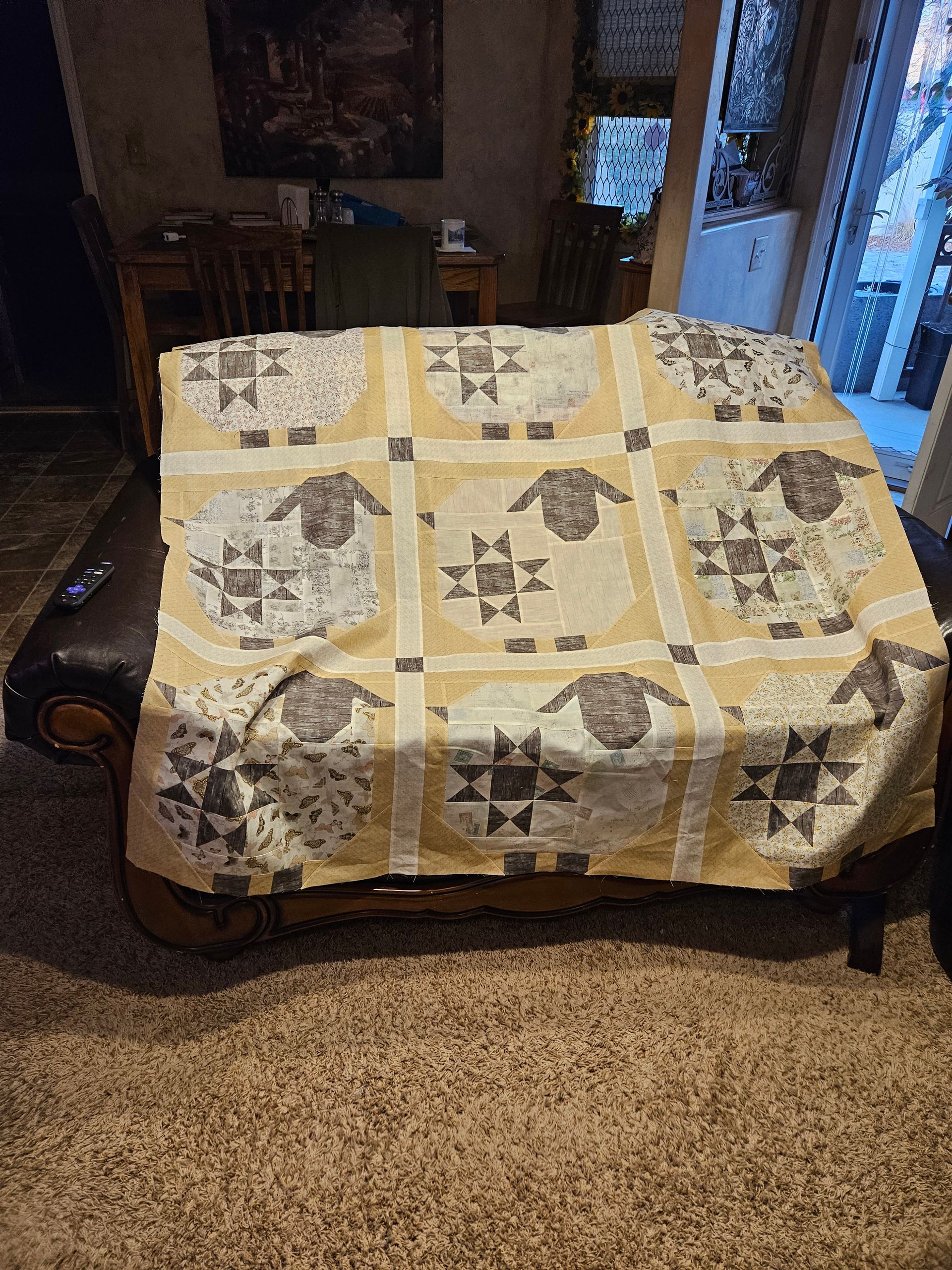 Living room with a tan quilted couch and patterned throw blanket on a dark shag rug.