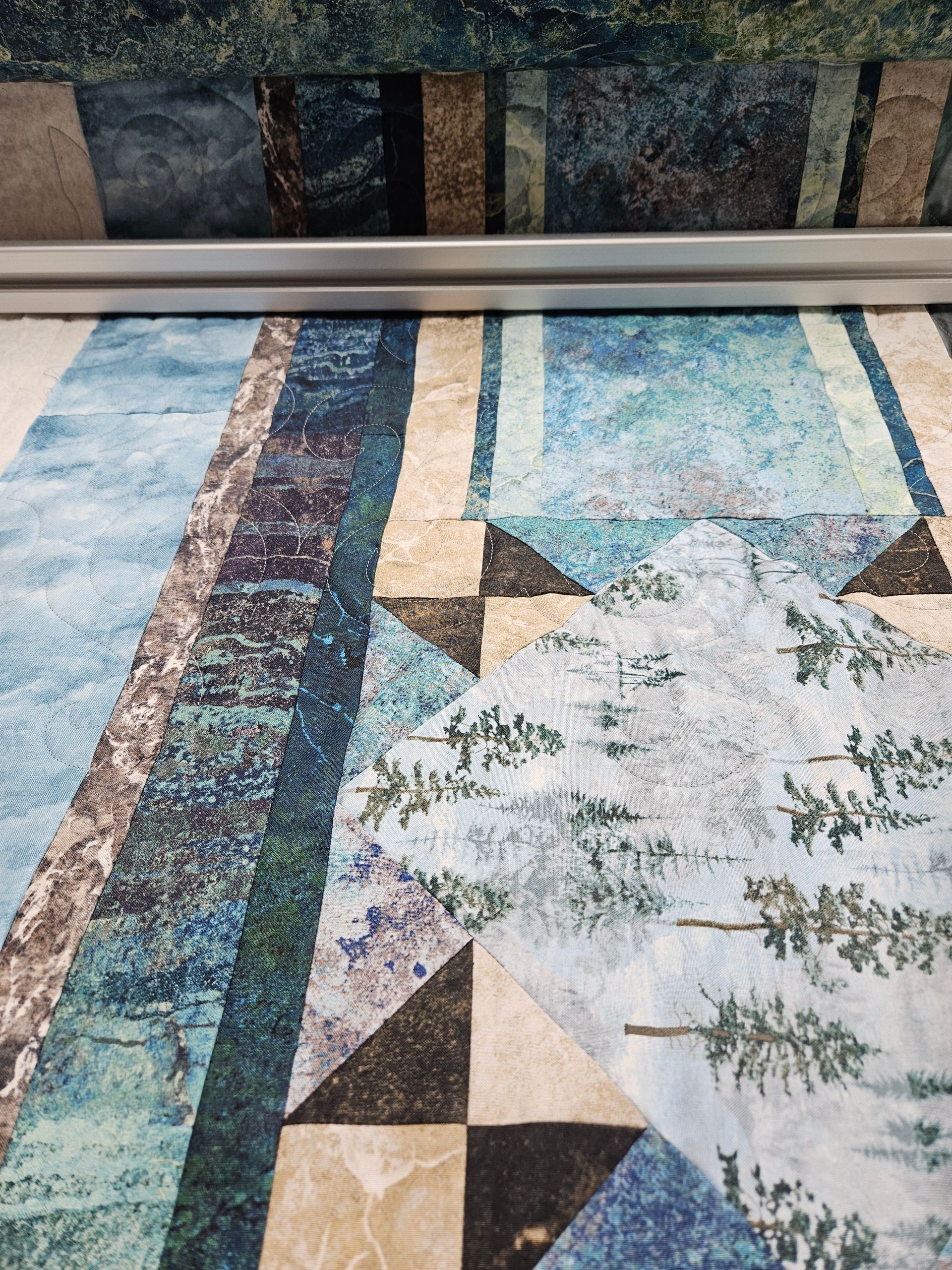 Colorful geometric quilt with blue, tan, and white triangular and leaf-like patterns