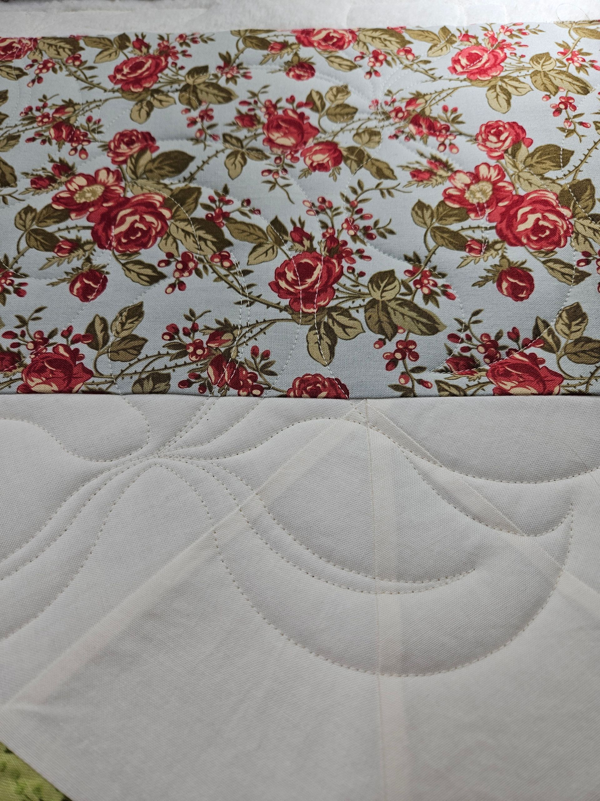 Floral red-and-pink fabric above a white quilted mattress cover with circular stitching