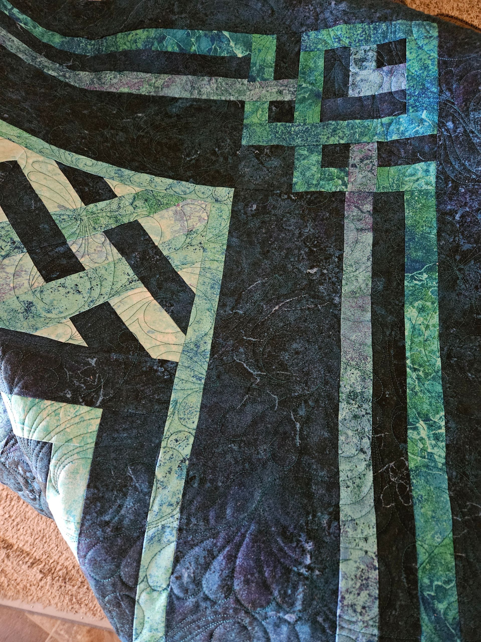 Abstract geometric quilt with teal, black, beige, and green patterned blocks