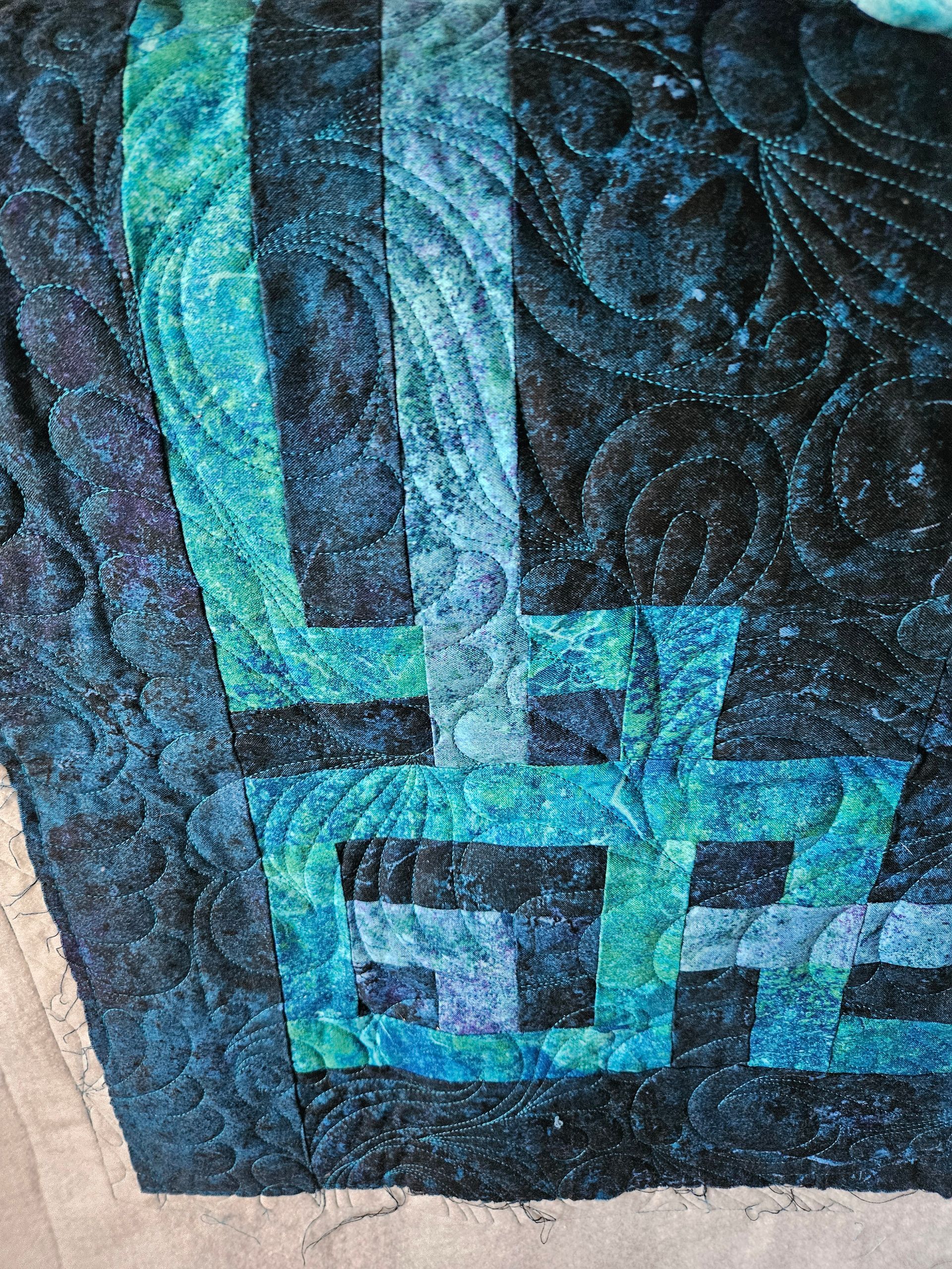 Close-up of a dark blue textile with turquoise and white geometric woven pattern.