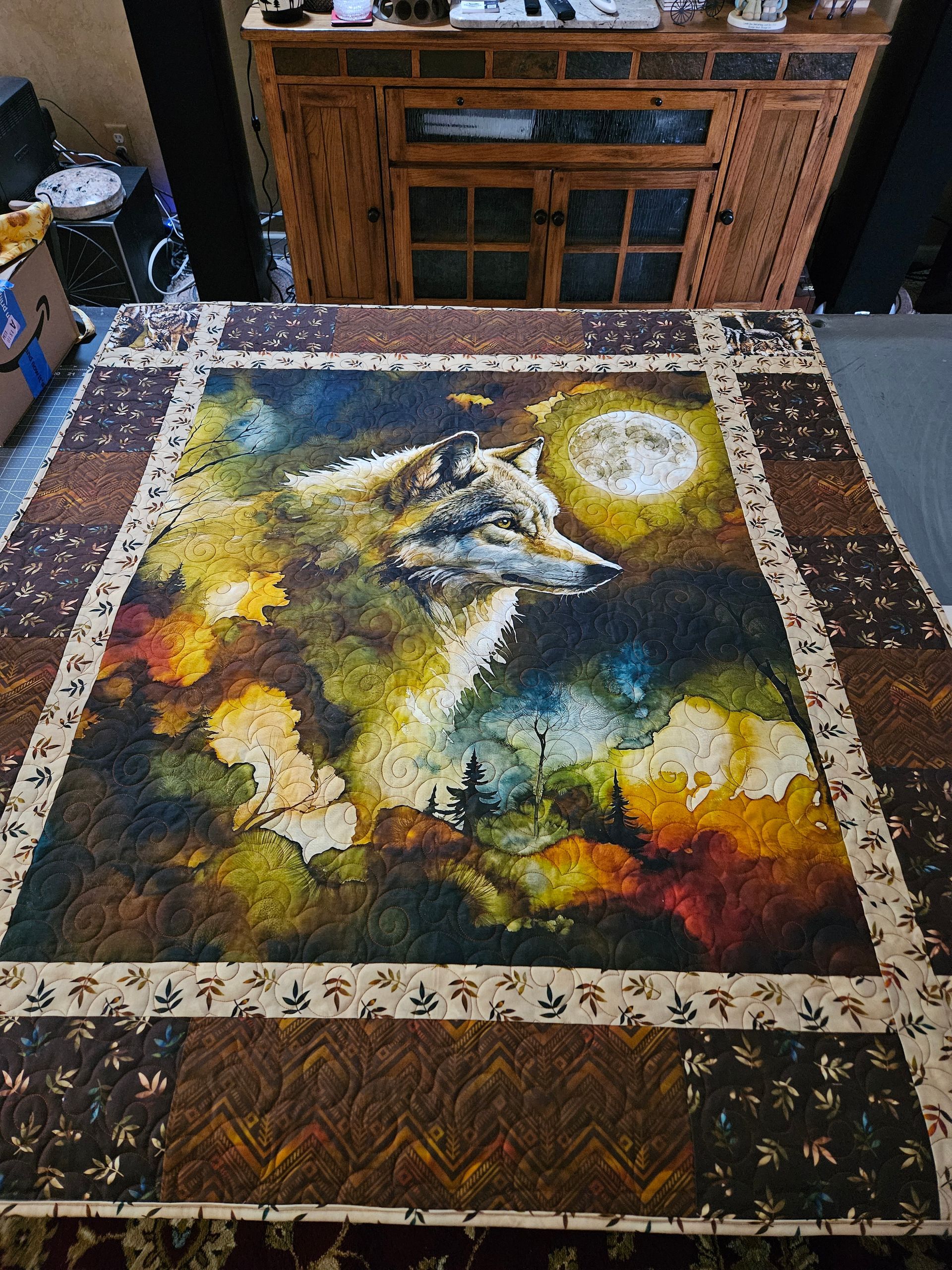 Abstract colorful painting on a large rug or canvas, with a bright moon-like circle and dark brown border.