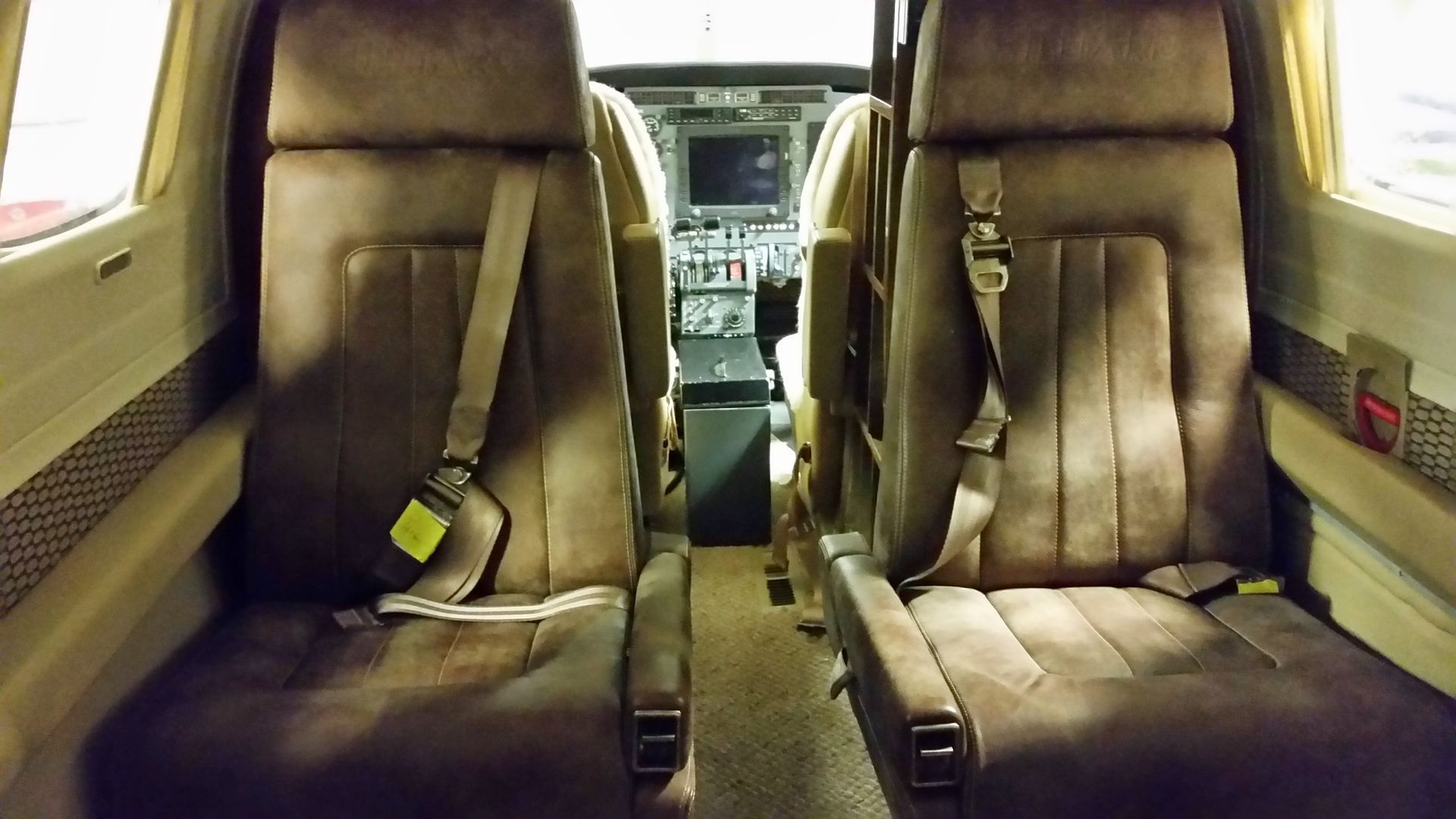 Interior of a private jet with brown leather seats facing each other and a central aisle.