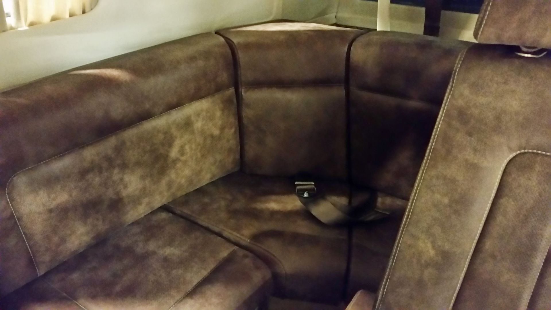 Brown leather sectional sofa with a corner seat and a small remote on the cushion